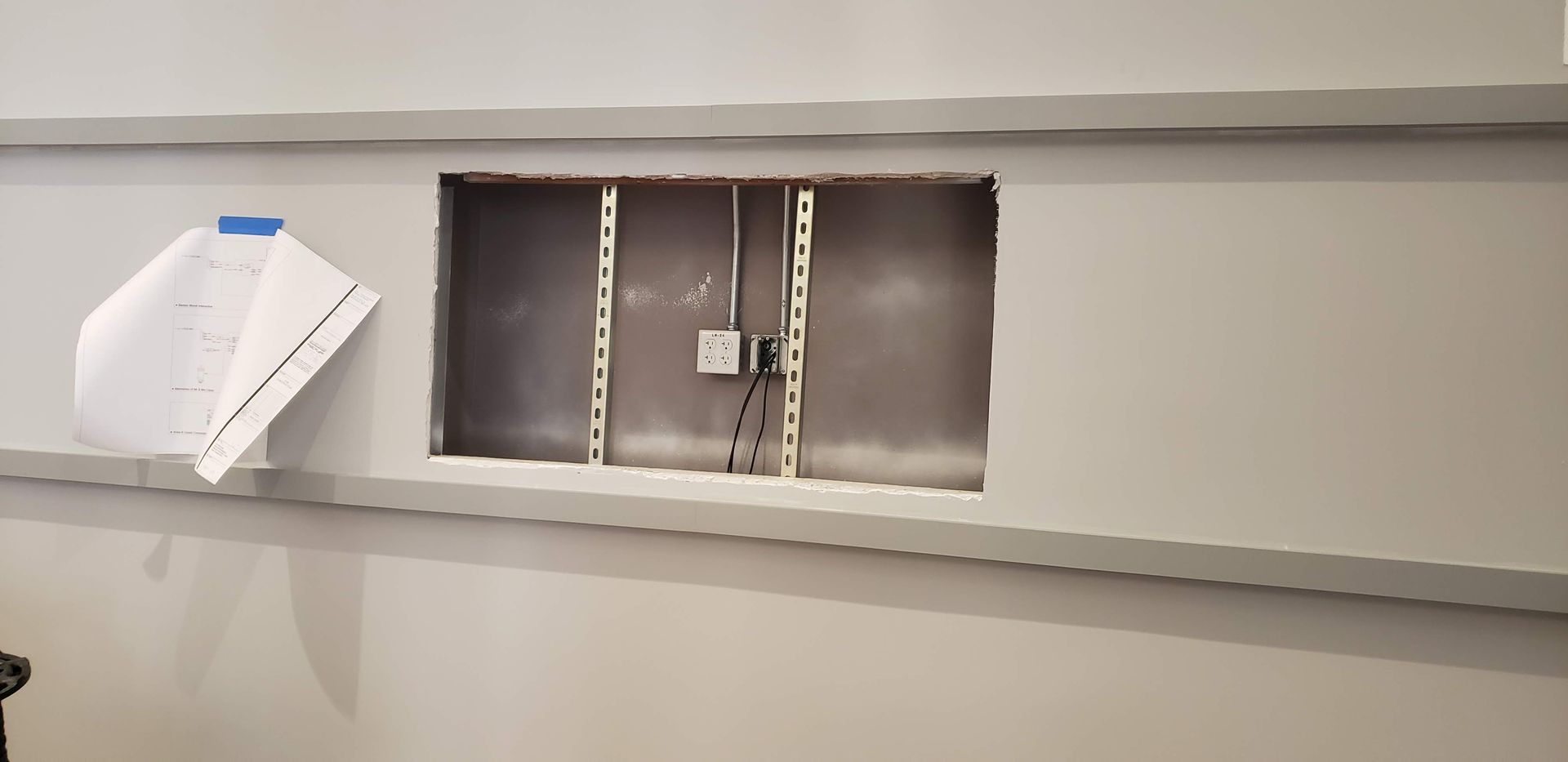 A white wall with a hole in it that looks like a door.