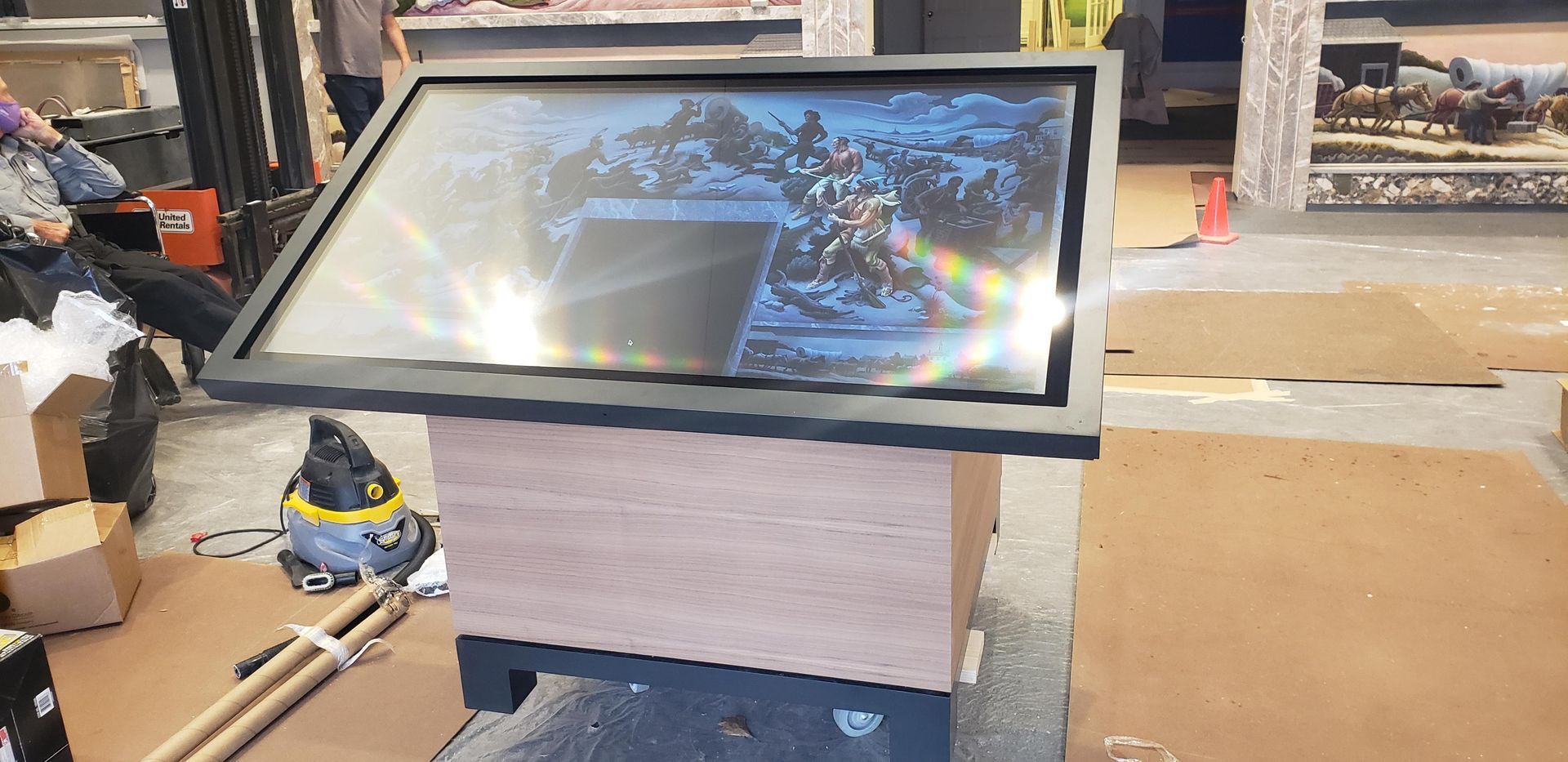 A large flat screen tv is sitting on top of a wooden table.