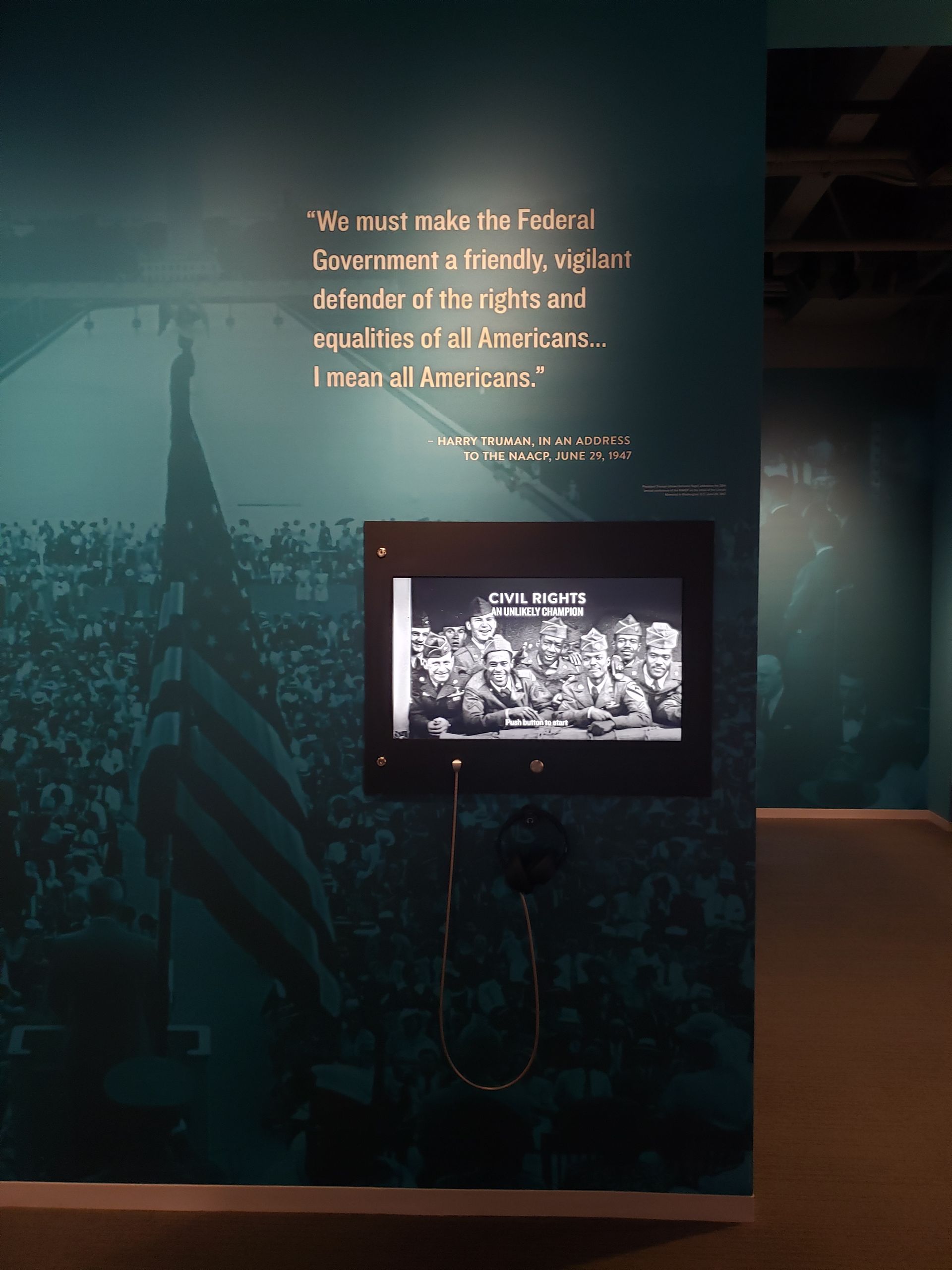 A wall with a picture of a crowd and a quote on it