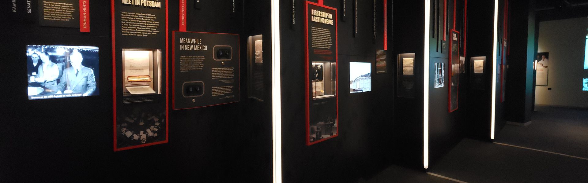 A hallway with a lot of signs on the wall and a lot of televisions on the wall.