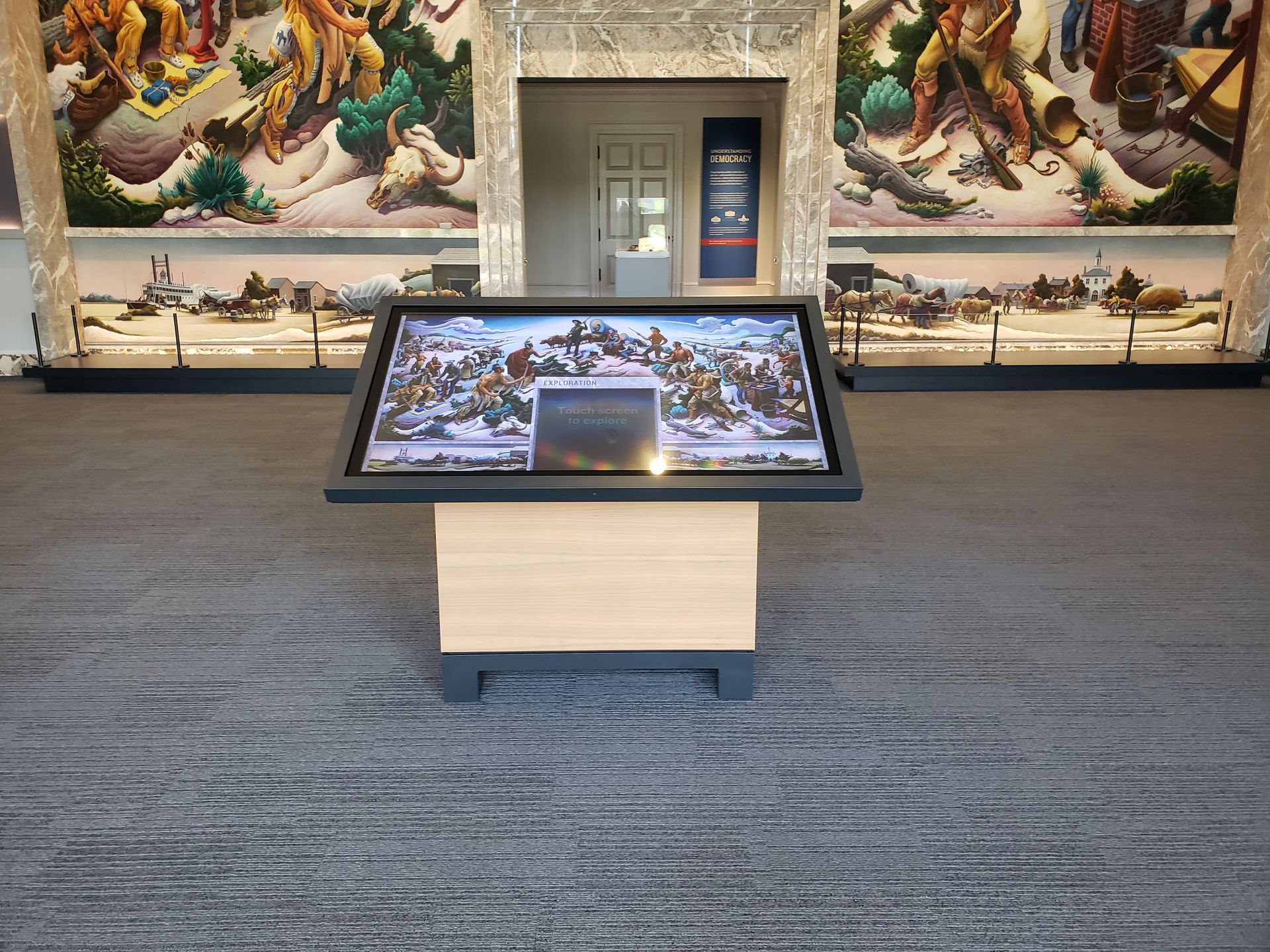 A table with a screen on it in a room with paintings on the wall.