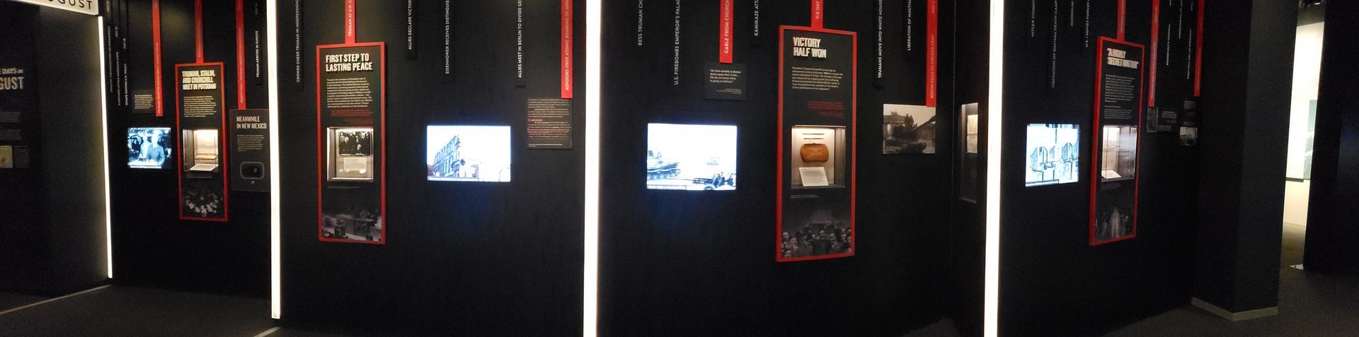 A row of screens hanging from the ceiling in a dark room.