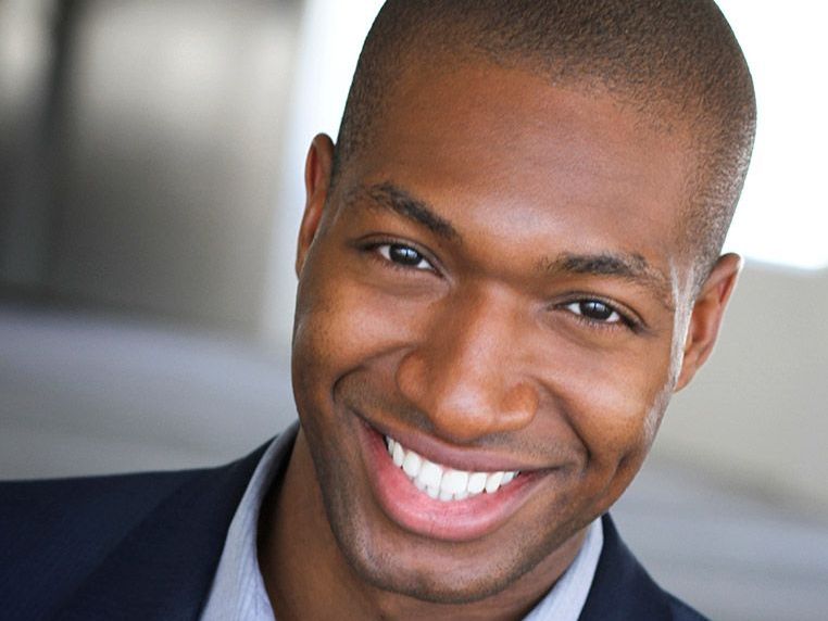 A man in a suit and tie is smiling for the camera