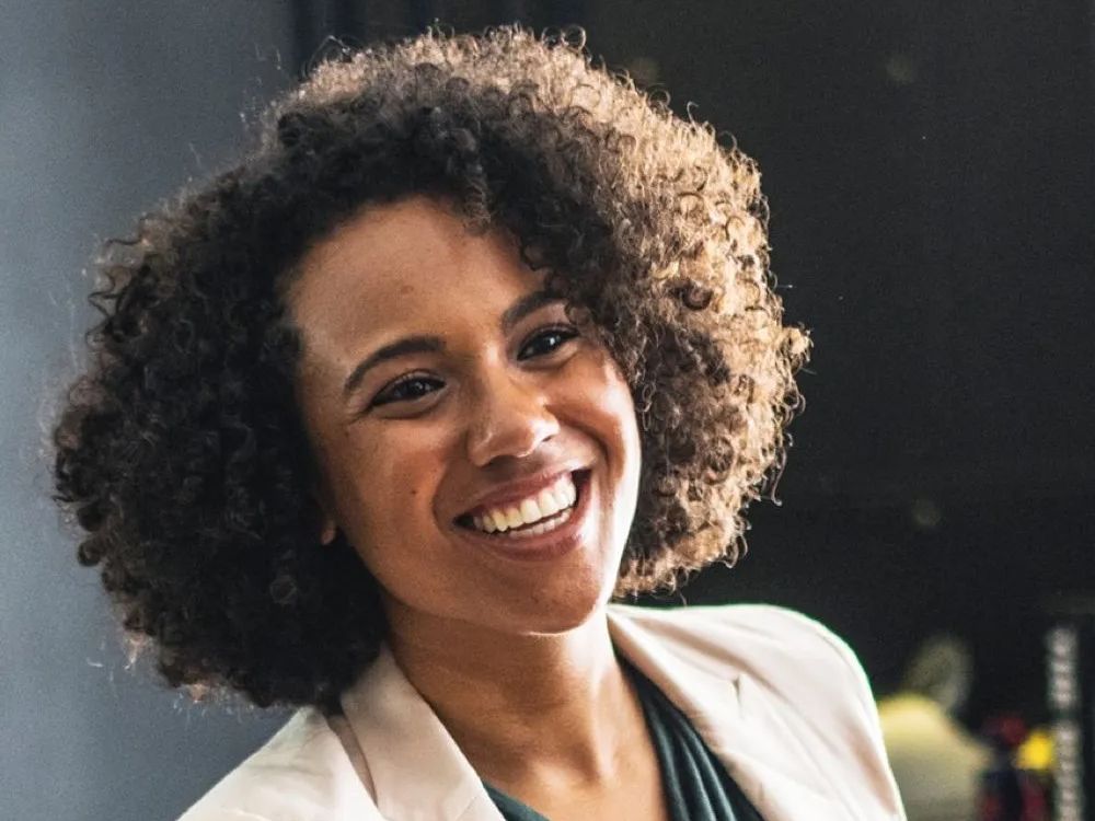 A woman with curly hair is smiling for the camera