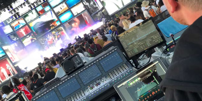 A man is sitting in front of a mixer at a concert.