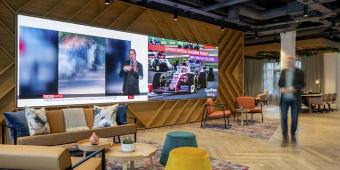 A man is standing in front of a large screen in a living room.