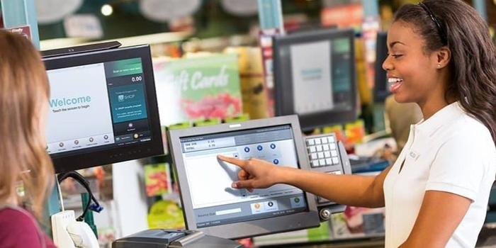 A woman is pointing at a computer screen in a grocery store.