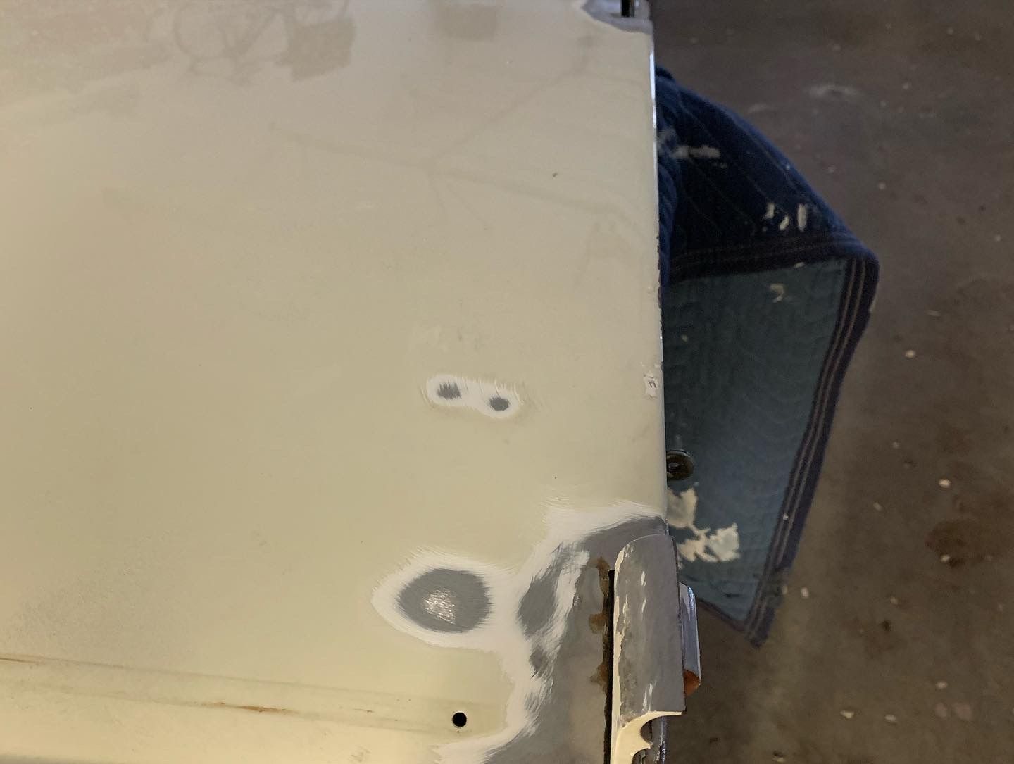 Close-up of a beige wall with a damaged corner and a small blue object beside it on a concrete floor