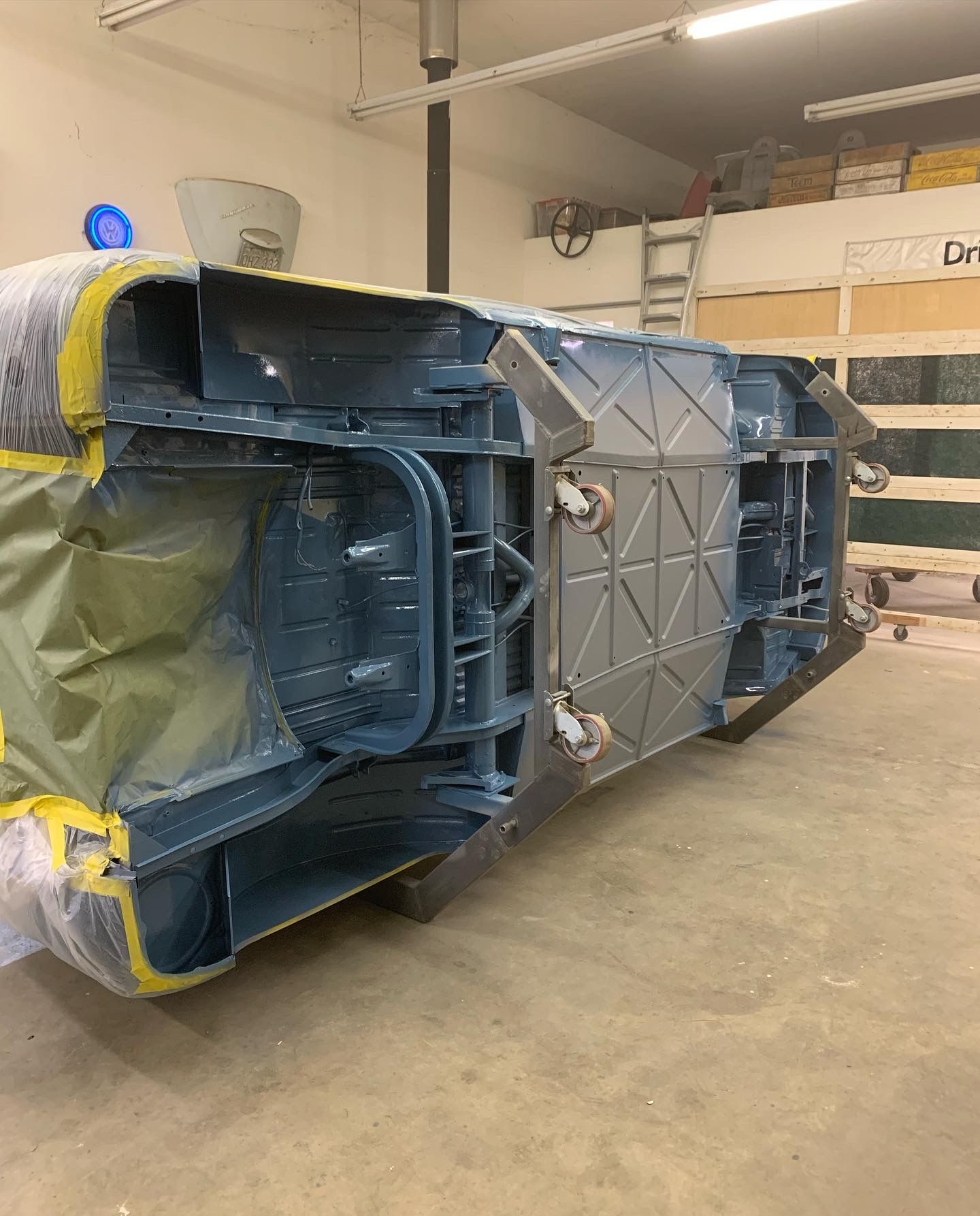Large blue industrial machine wrapped in yellow plastic, lying on its side in a warehouse.