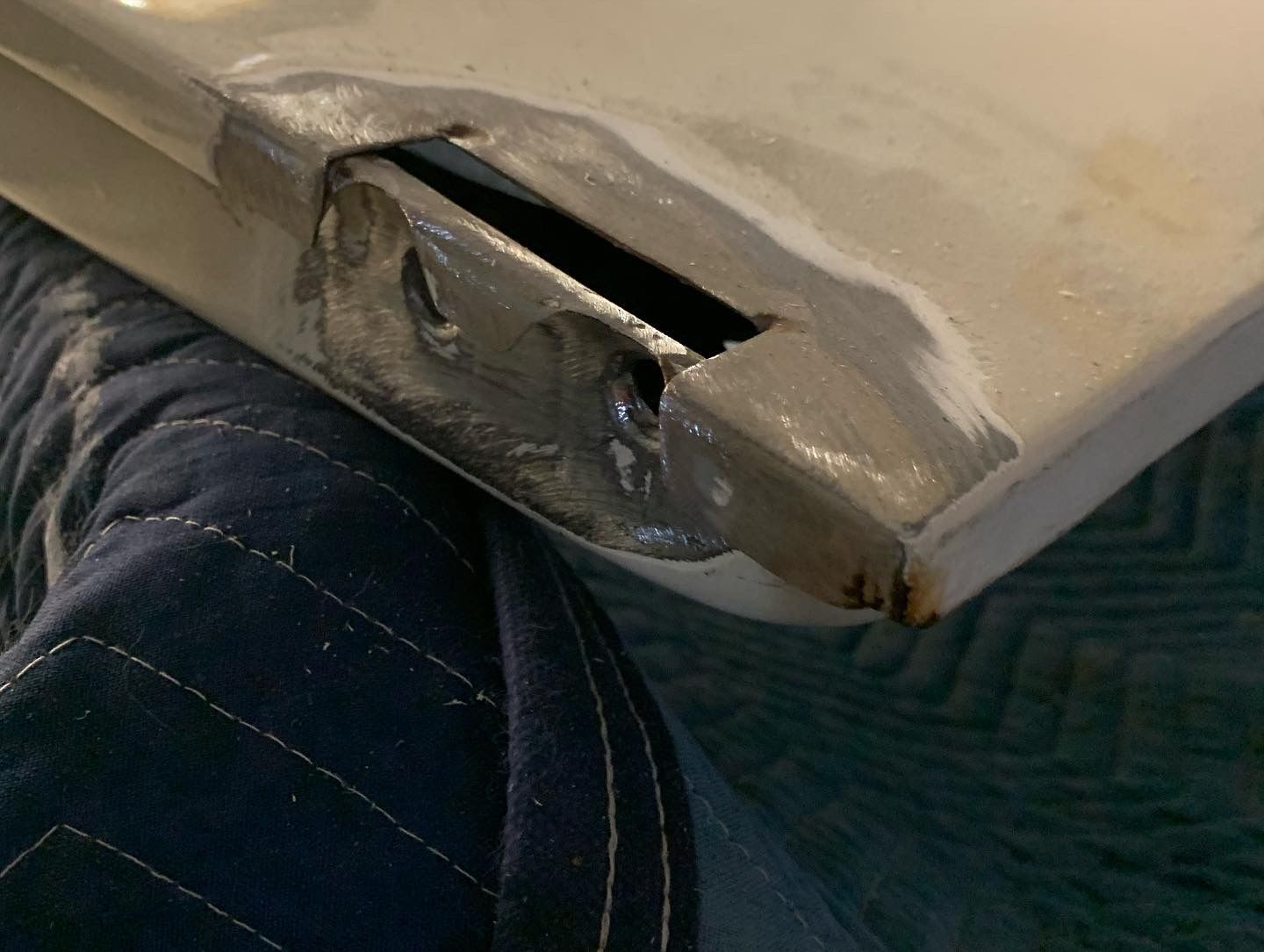 Close-up of a damaged beige car bumper with a broken corner and exposed internal parts