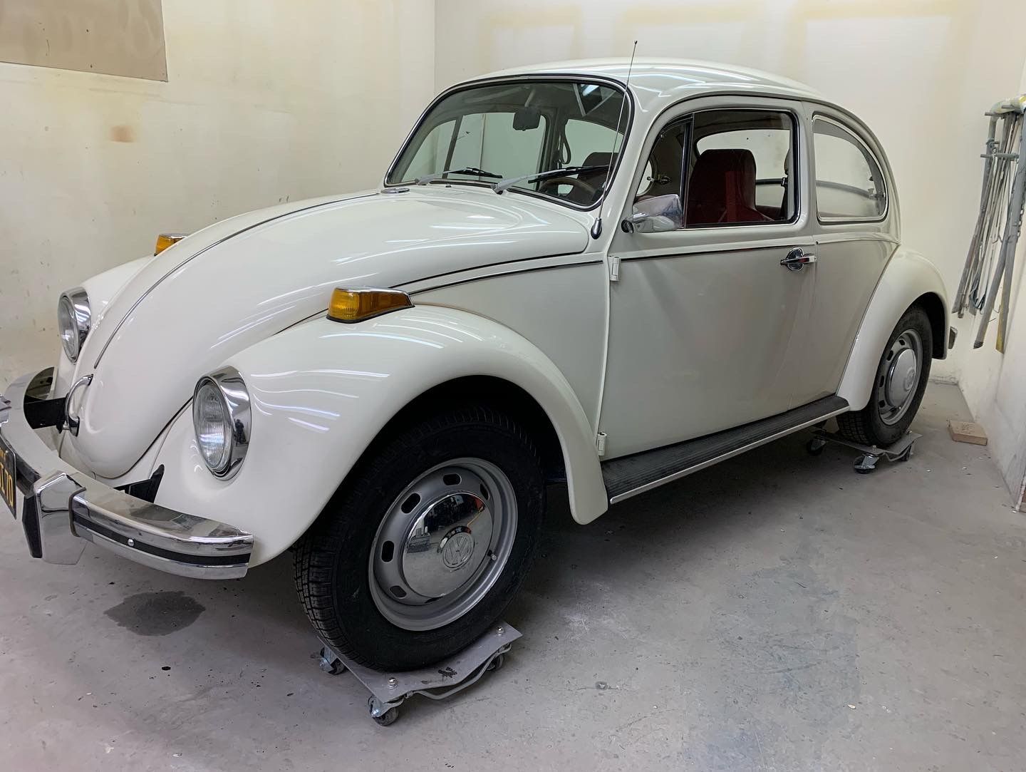 White vintage Volkswagen Beetle parked indoors in a studio-like garage