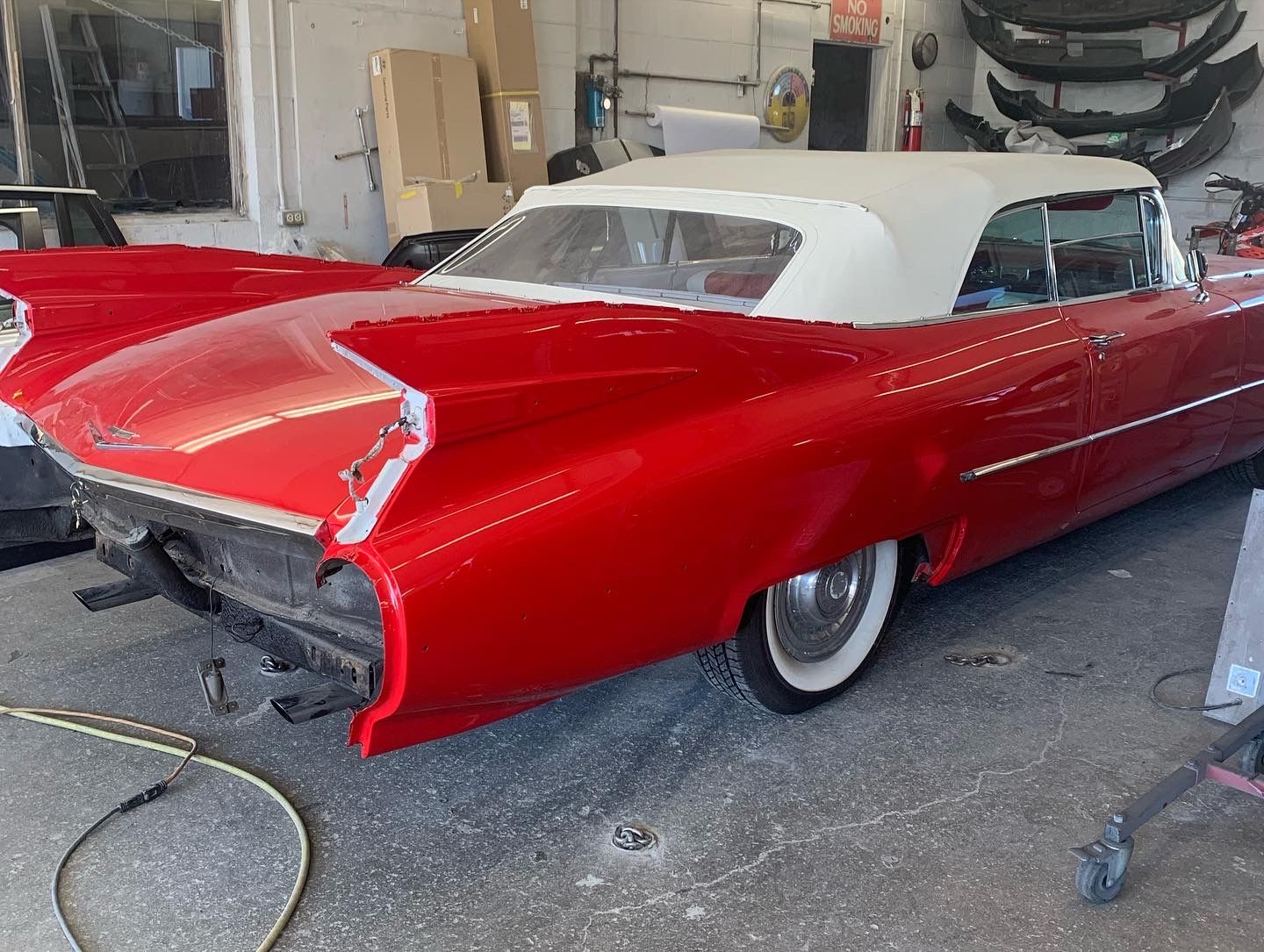 Classic red-and-white convertible car parked in a garage, rear view
