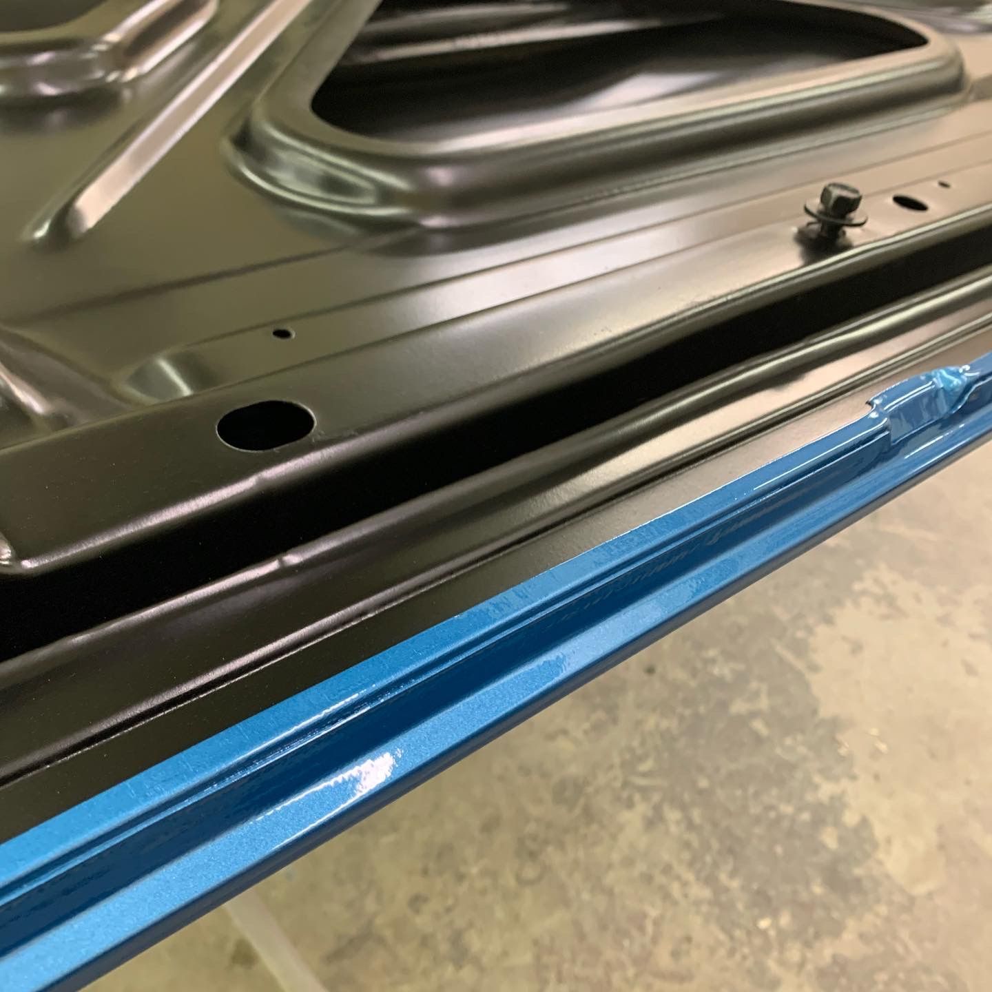 Close-up of a black metal panel with a blue protective strip along the edge.