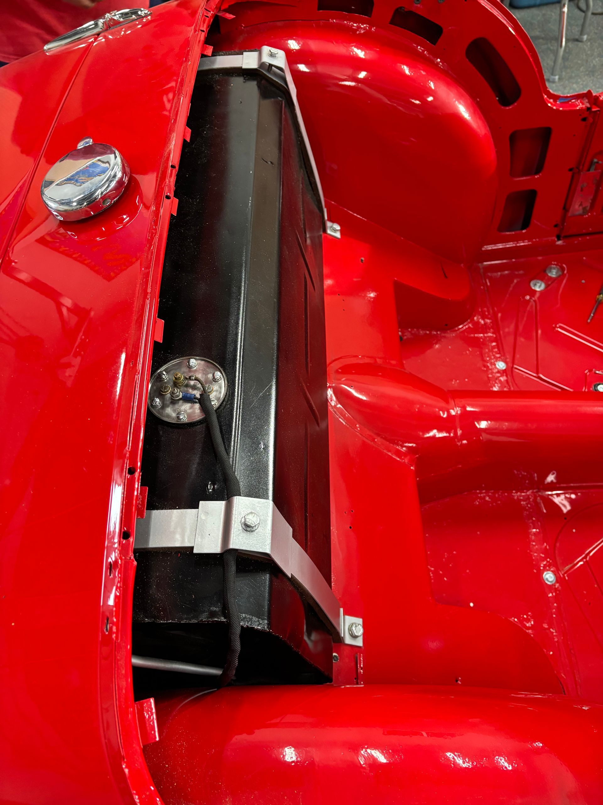 Close-up of a red vehicle interior with a black seatbelt or belt strap and metal hardware