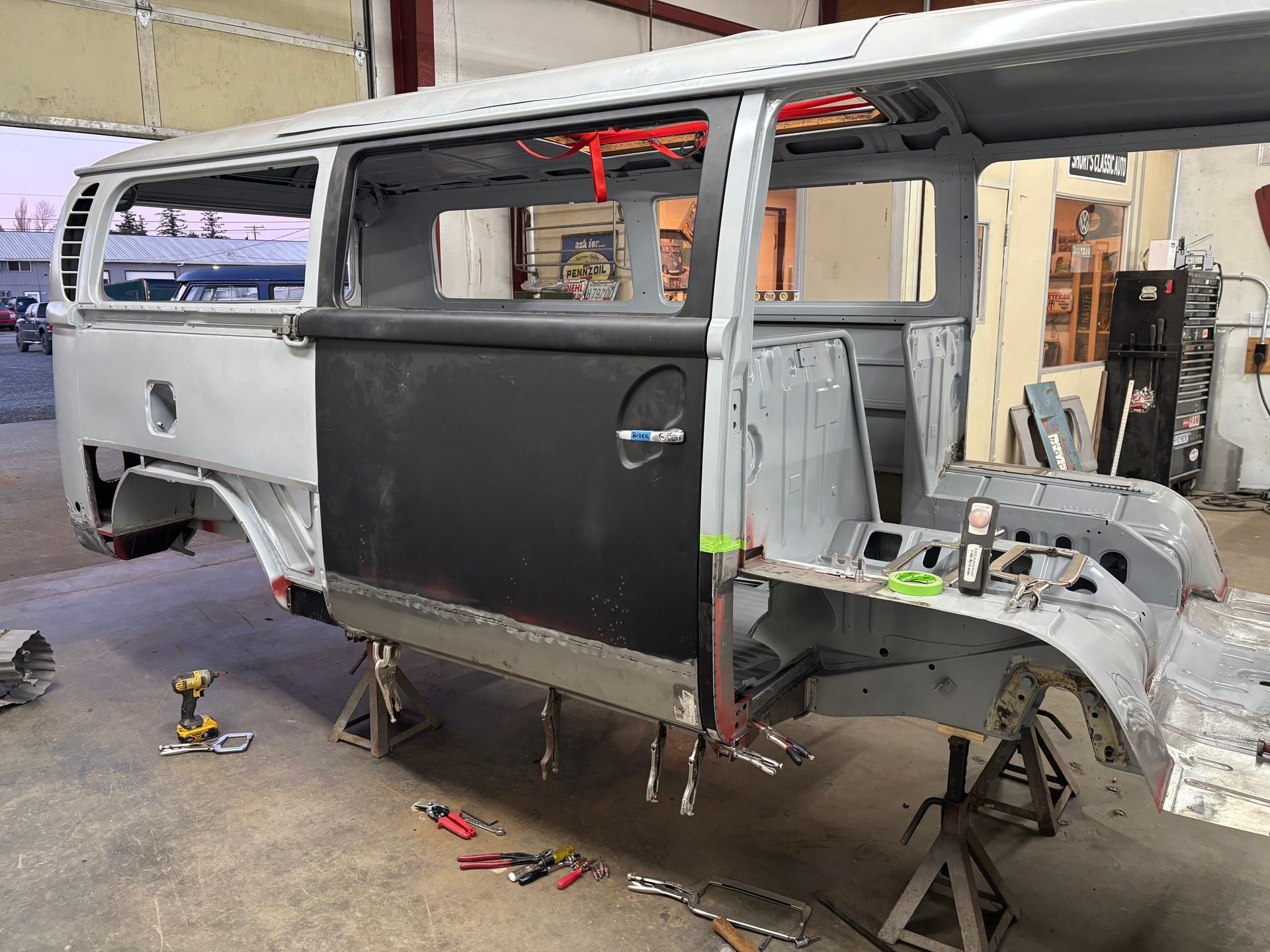 Partially stripped van in a workshop, with exposed frame and unfinished body panels.