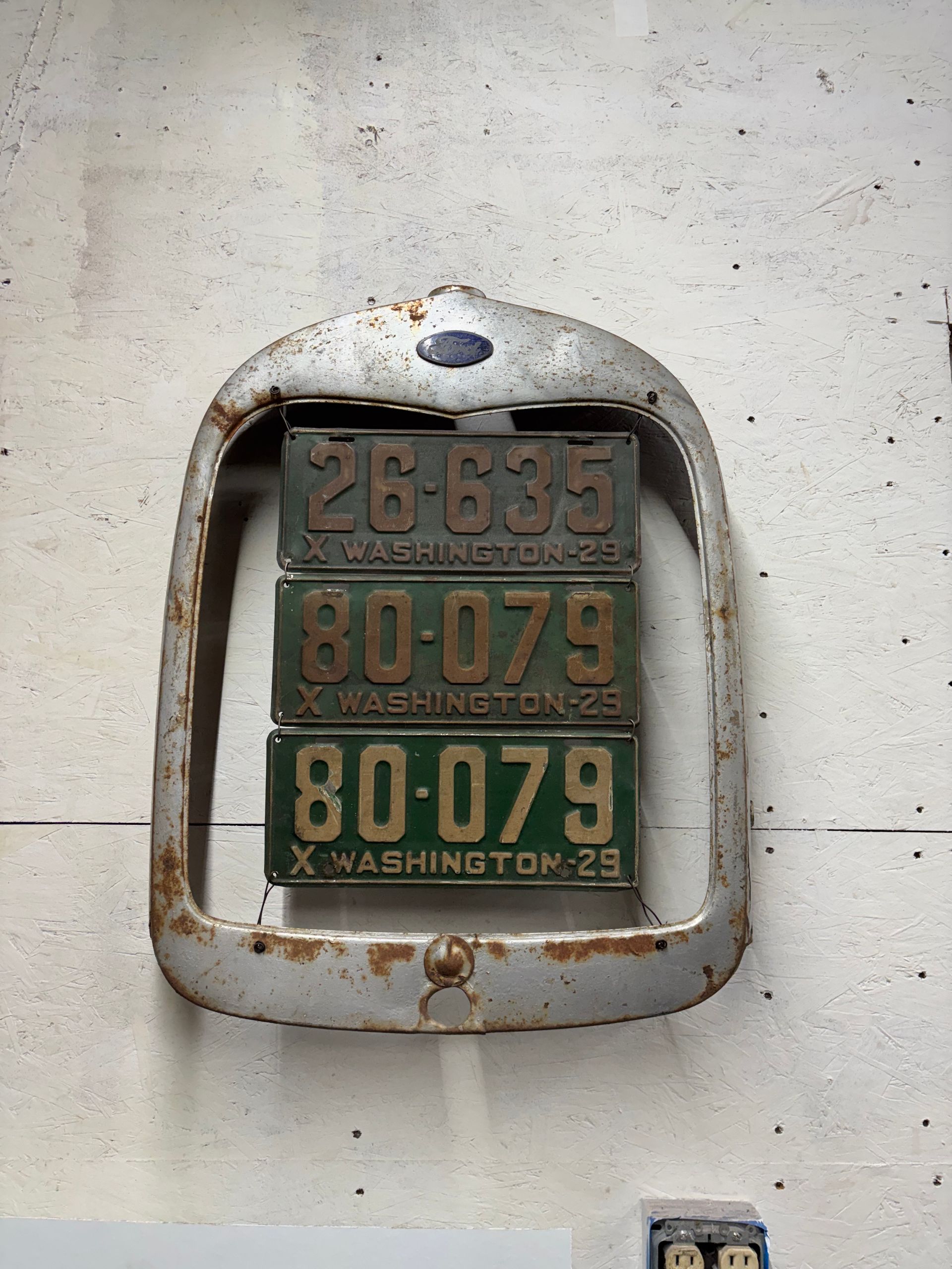 Weathered wall-mounted number display with rusted metal frame and green-orange digits on a concrete wall