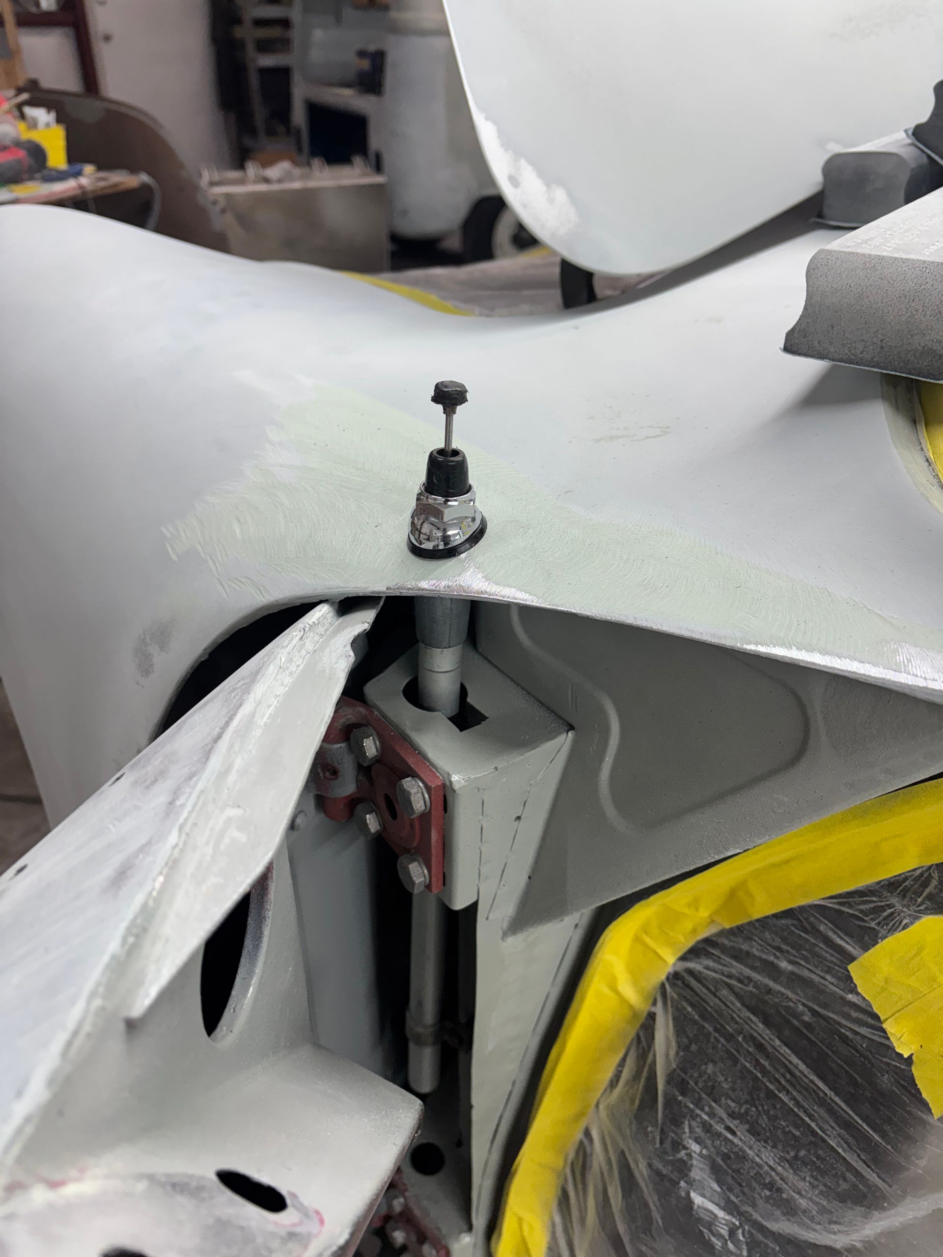 Close-up of a gray sculpted surface with a metal clamp and black knob in a workshop setting