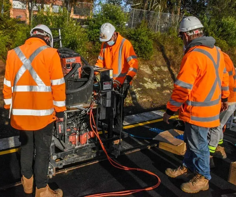 A group of construction workers are working on a machine.