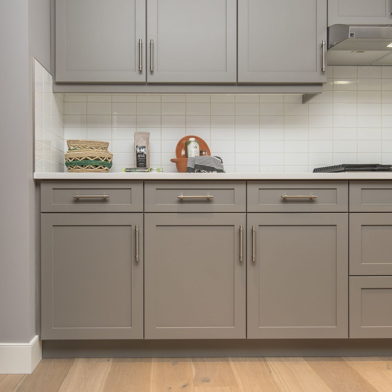 a kitchen with gray cabinets , drawers , and a stove top oven .