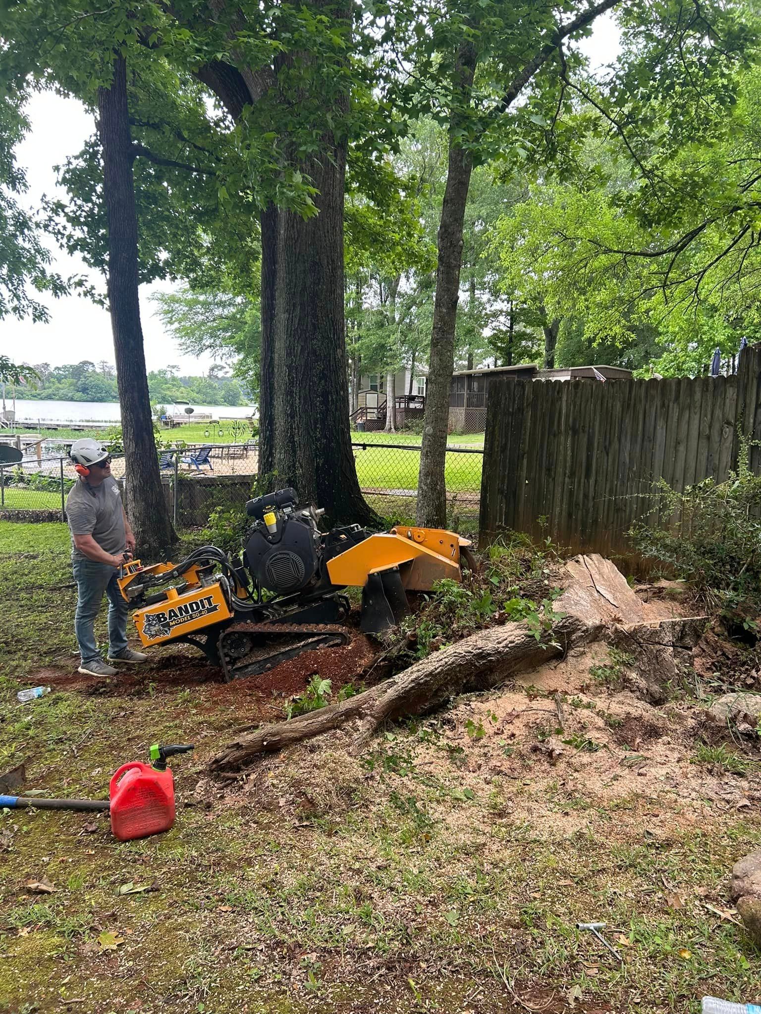 A man is standing next to a stump grinder in a yard.