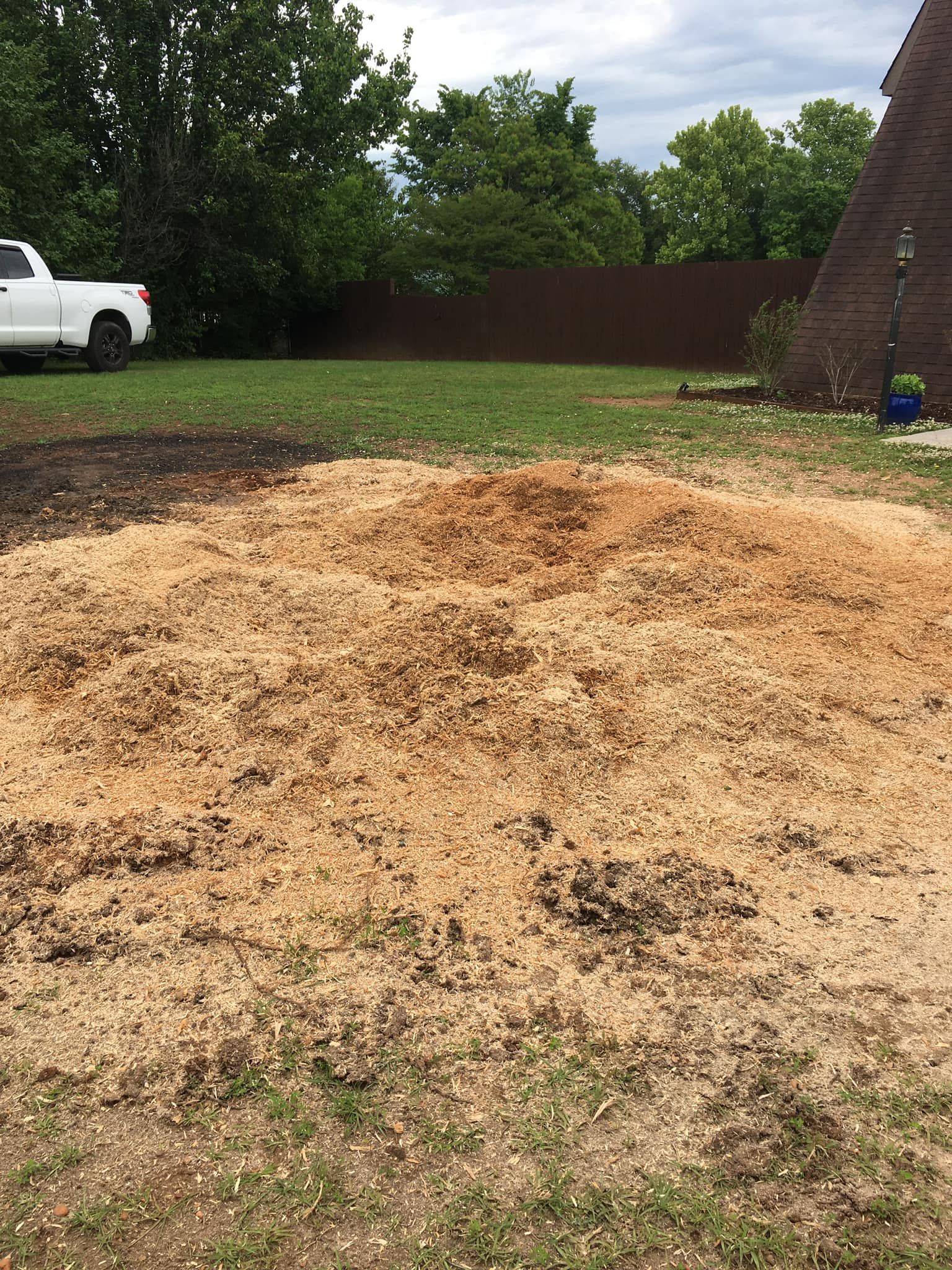 A white truck is parked next to a pile of dirt in a yard.