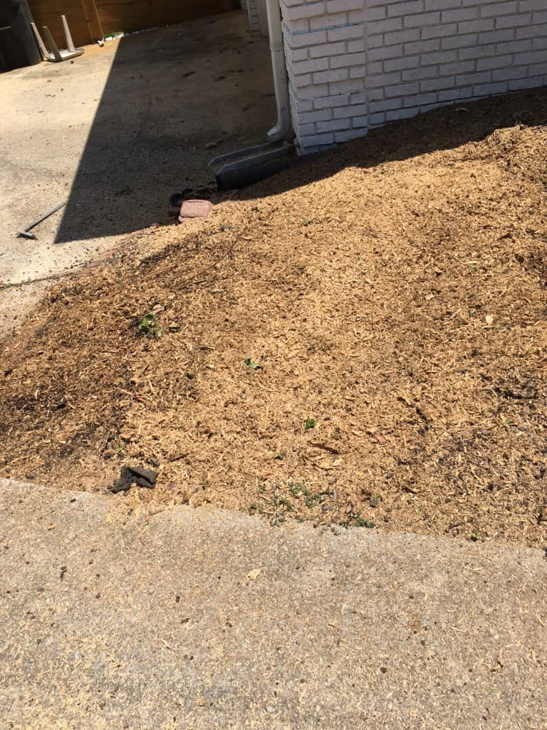A white brick house with a lot of dirt in front of it.