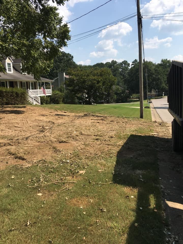A dumpster is parked in the grass in front of a house.
