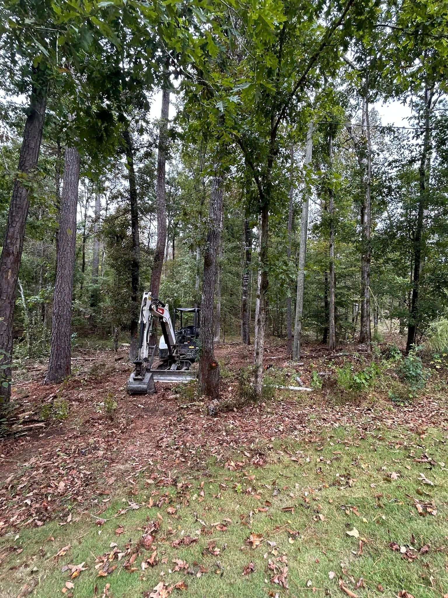 A small excavator is parked in the middle of a forest.