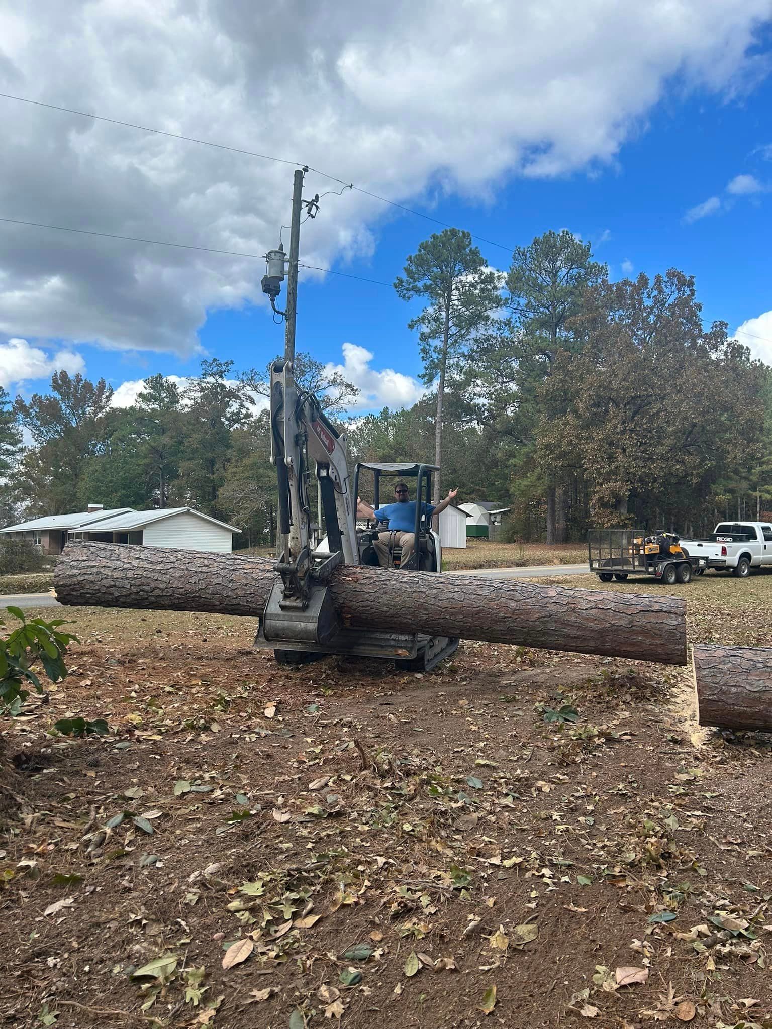 A large log is being lifted by a machine in a field.