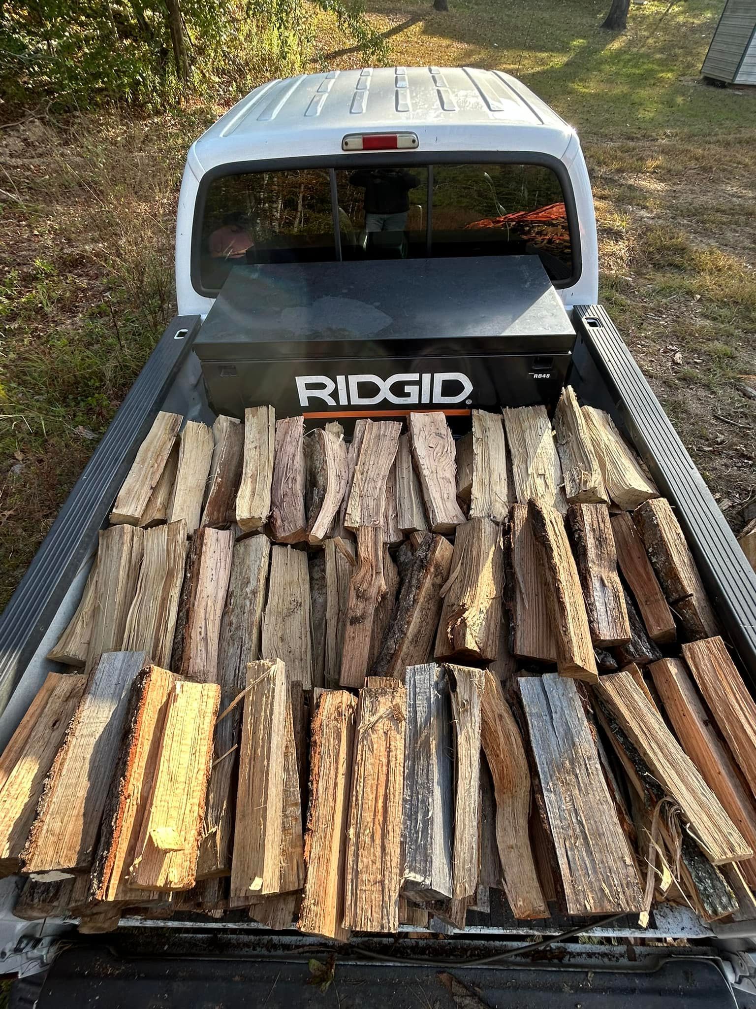The back of a truck is filled with wood.