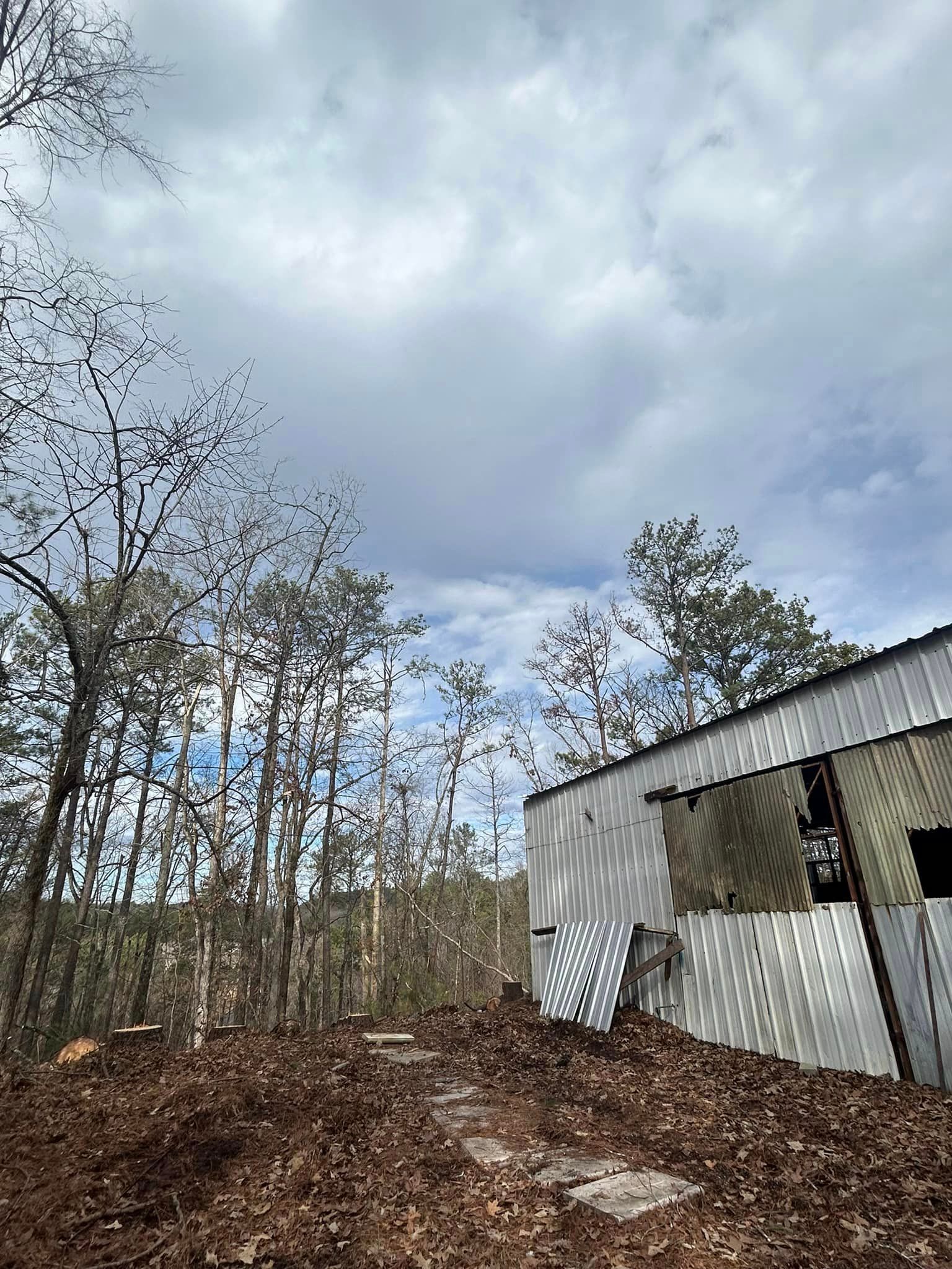 A white house is sitting on top of a hill in the middle of a forest.
