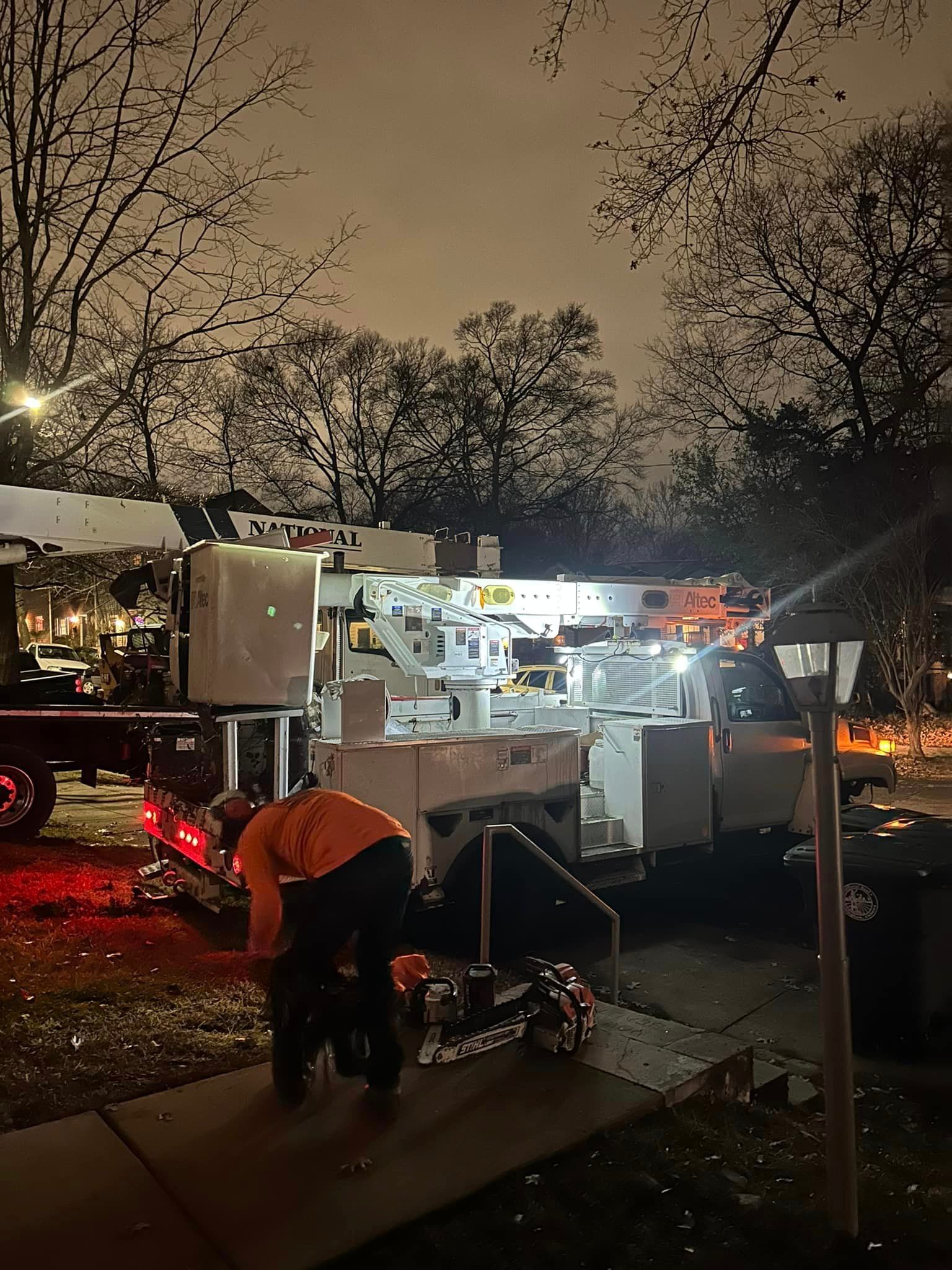 A man is working on a pipe in front of a truck at night.