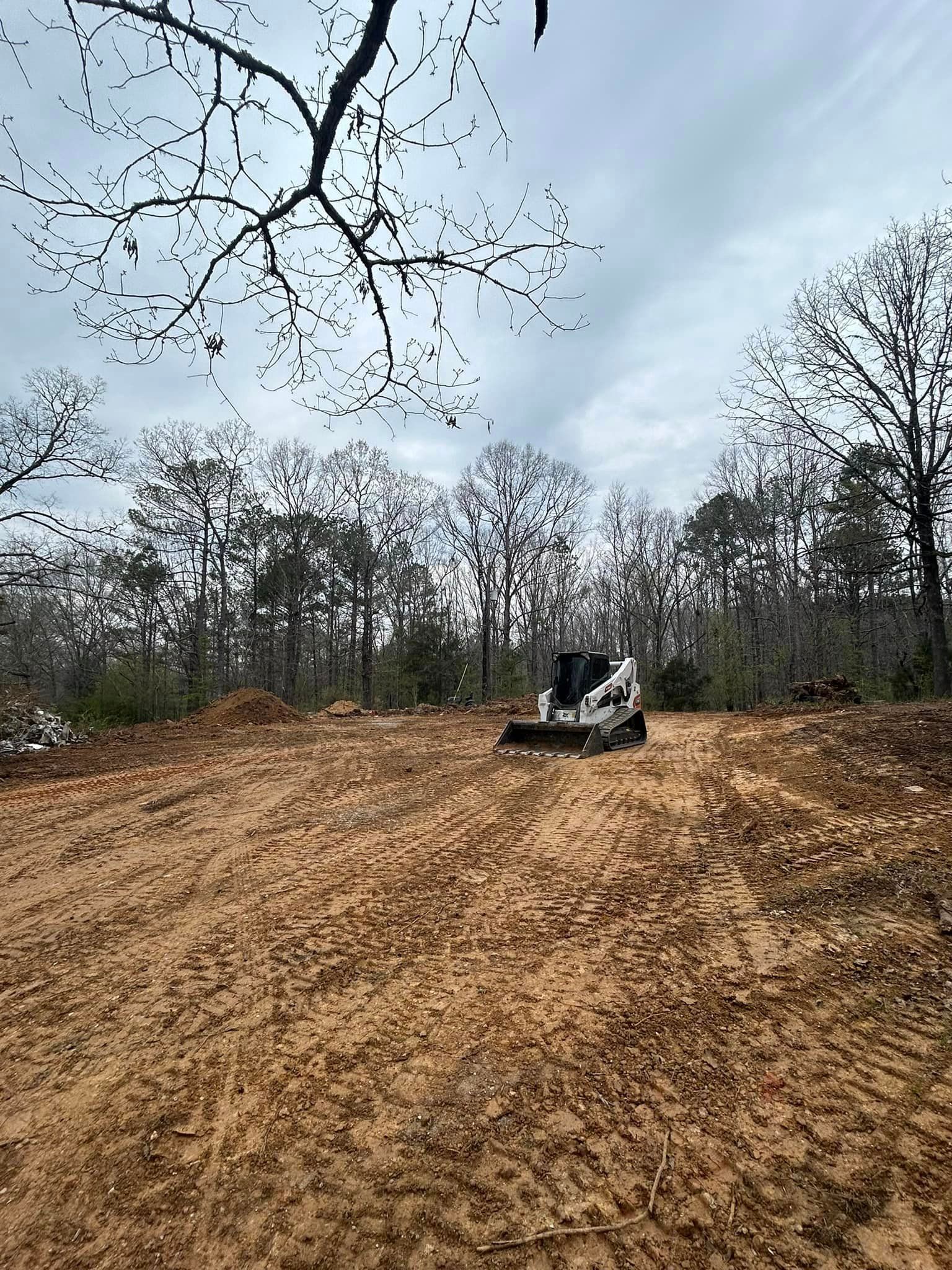 A bulldozer is driving down a dirt road in the middle of a forest.