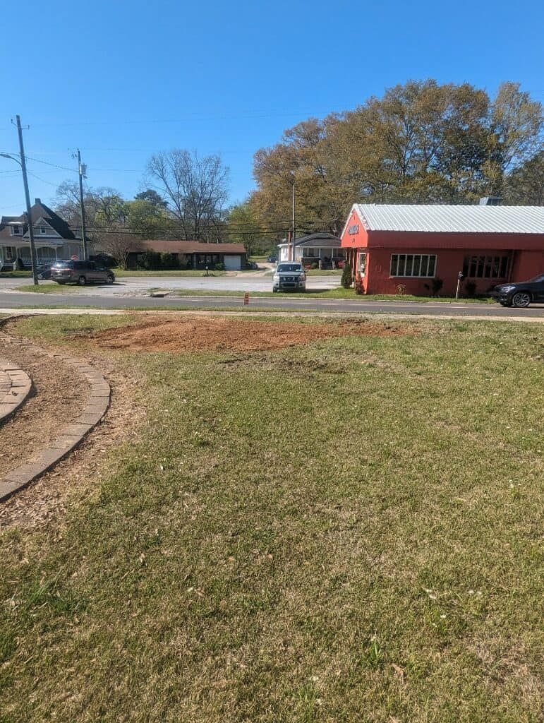 A large grassy field with a red building in the background.