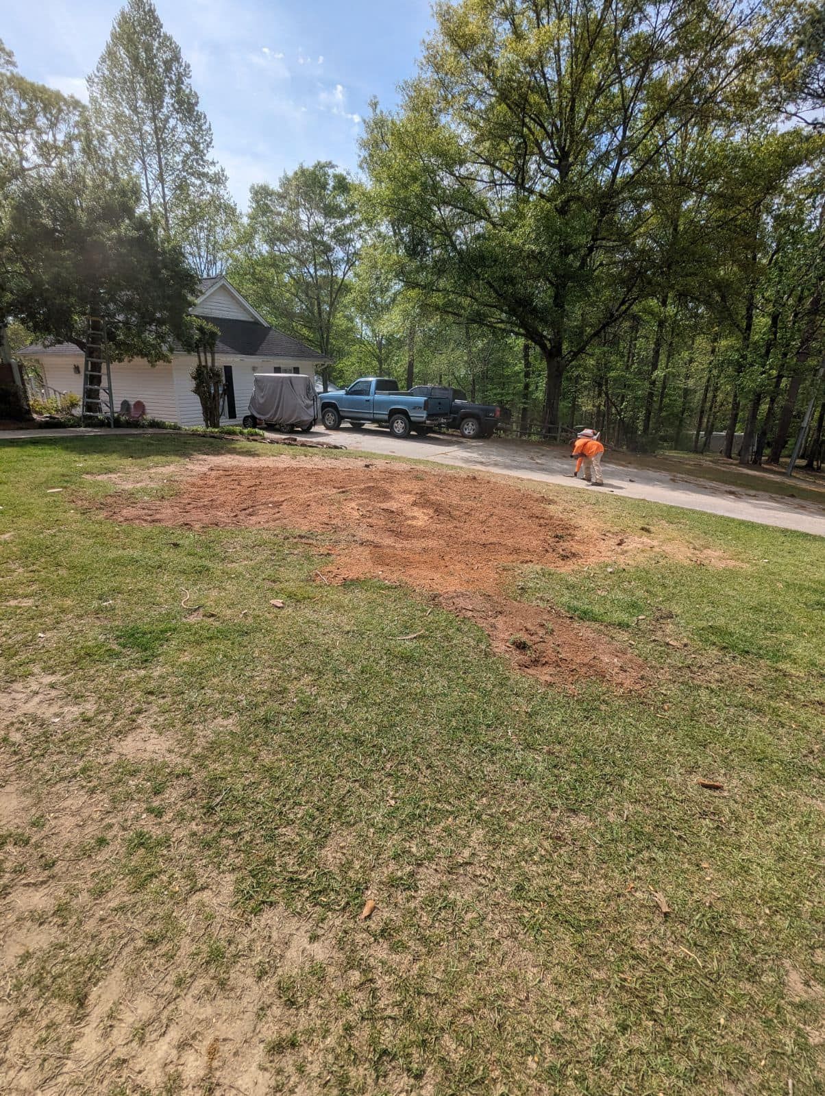 A blue truck is parked in the grass in front of a house.