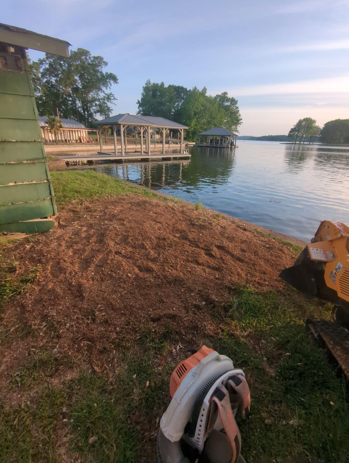 A blower is sitting on the grass next to a body of water.
