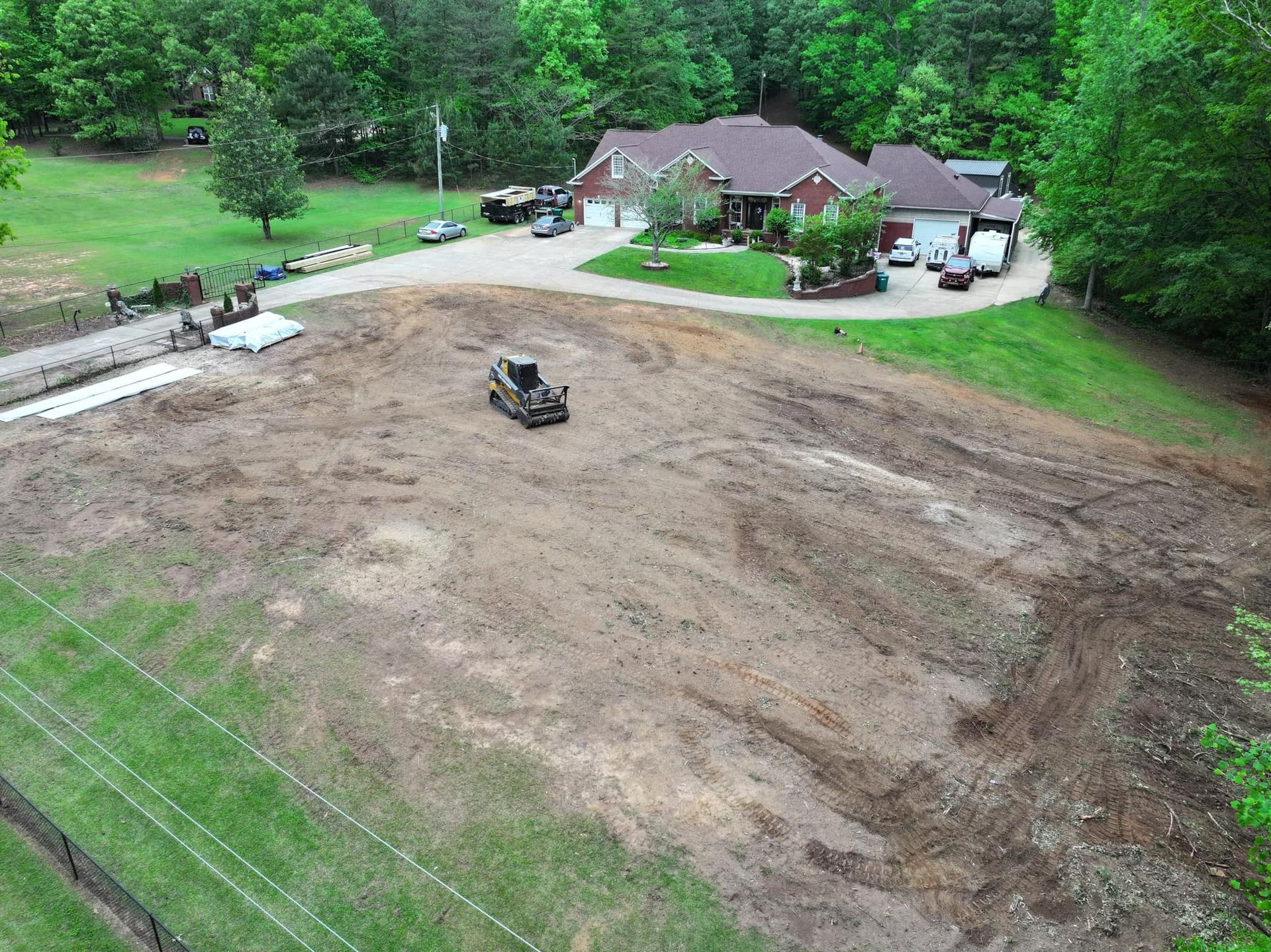 An aerial view of a large dirt field in front of a house.