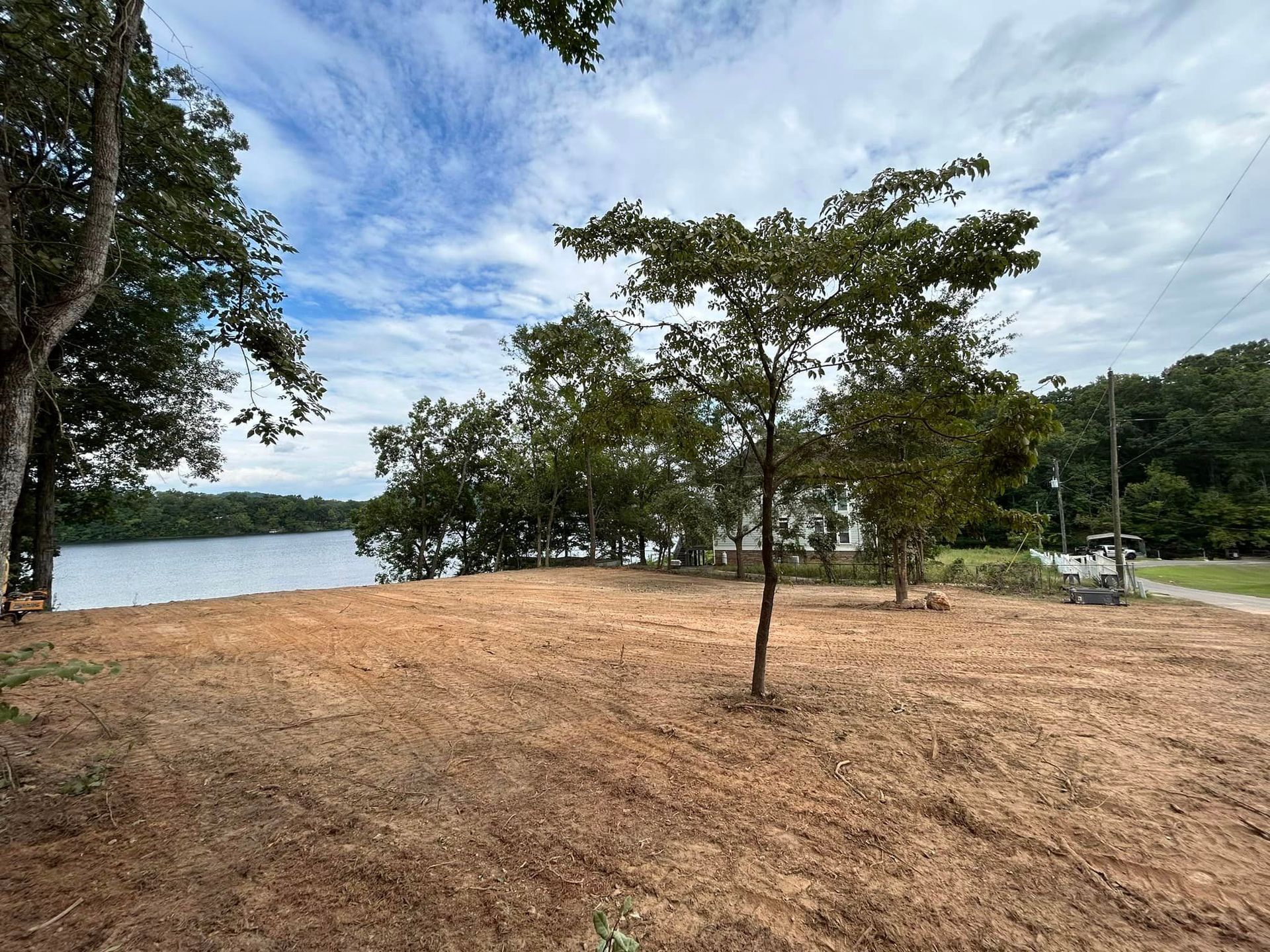 A dirt field with trees and a lake in the background