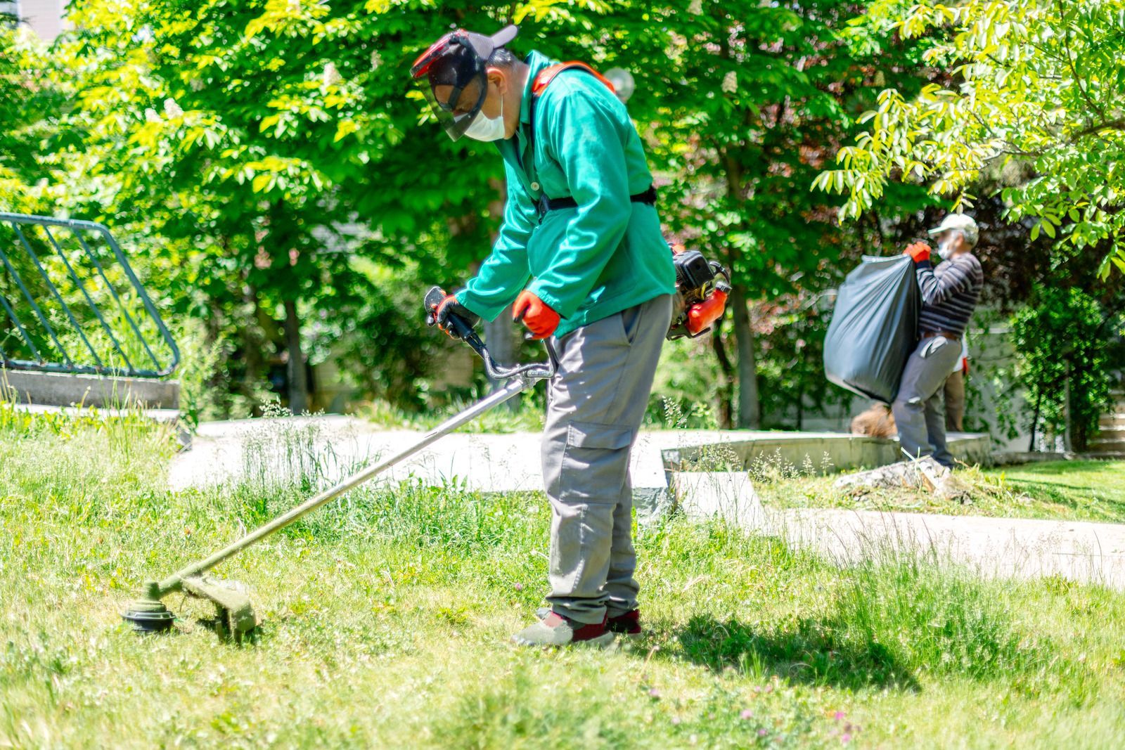 A man is using a lawn mower to cut the grass in a park.