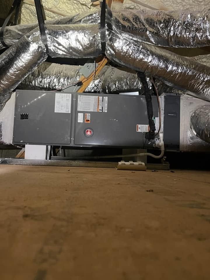 Gray HVAC unit with insulated ductwork in a basement crawl space