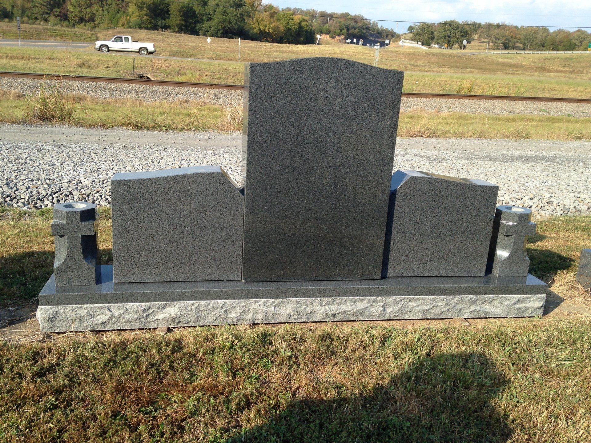A gravestone is sitting in the middle of a grassy field.