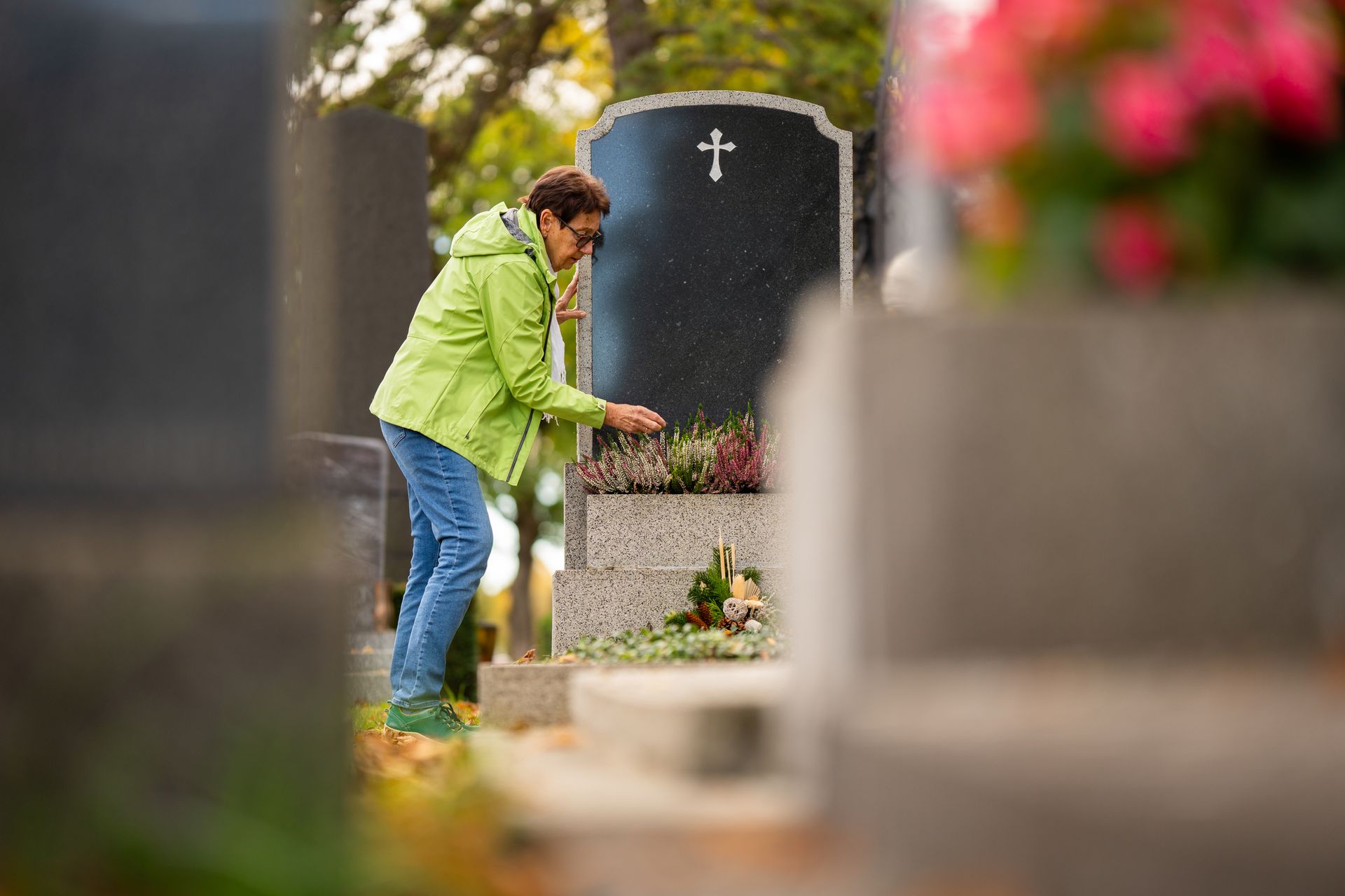 Woman standing at family grave arranging flowers and decoration in cemetery. Woman standing at family grave arranging flowers and decoration in cemetery.