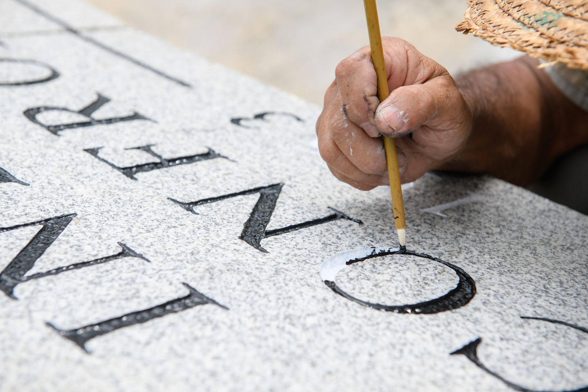 Stone mason painting on grave stone