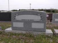 A gravestone is sitting in the middle of a cemetery.