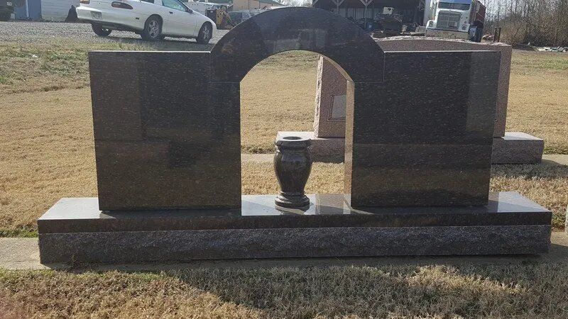 A gravestone with a vase in the middle of it