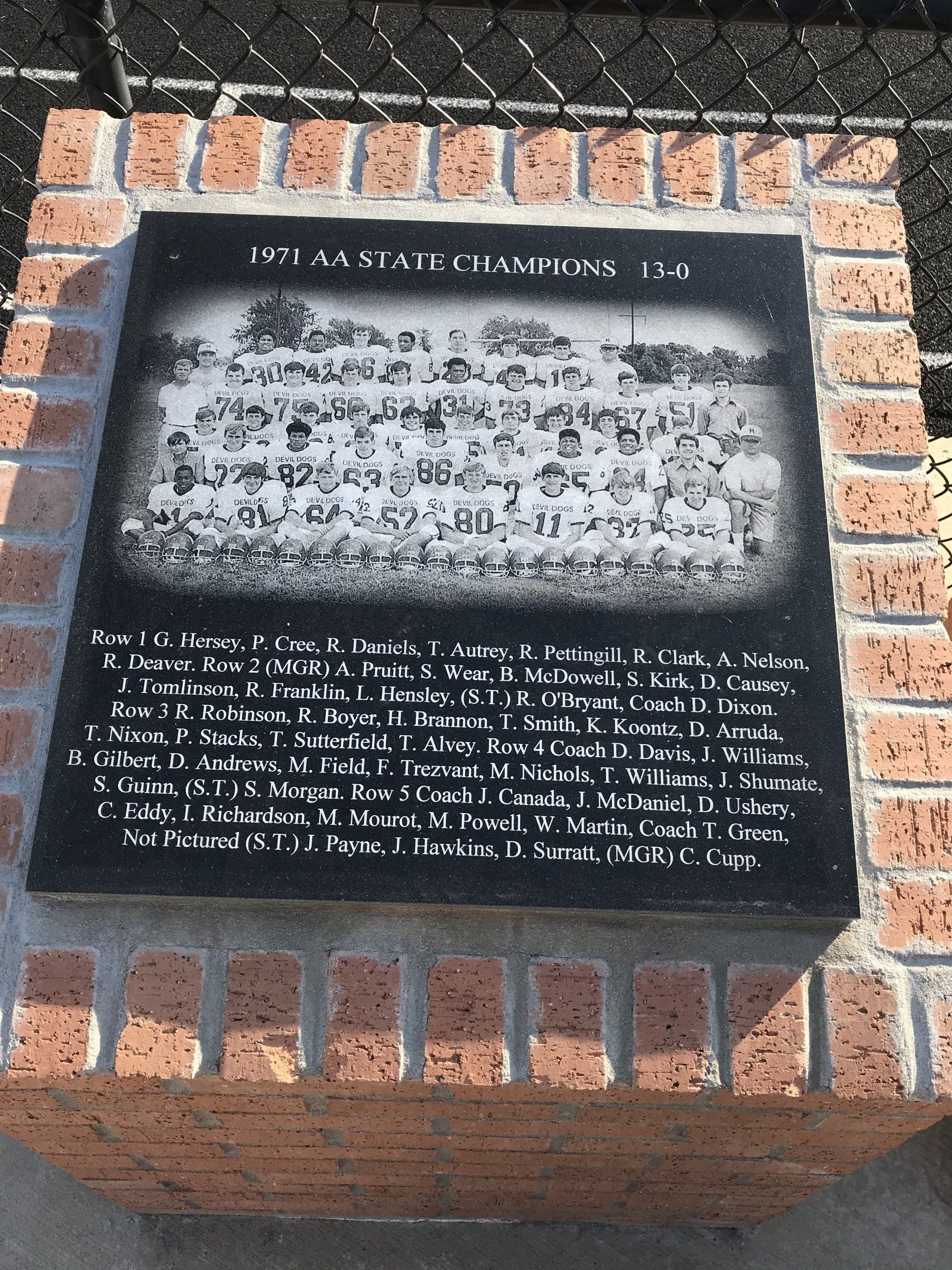 A black and white plaque is sitting on top of a brick wall.