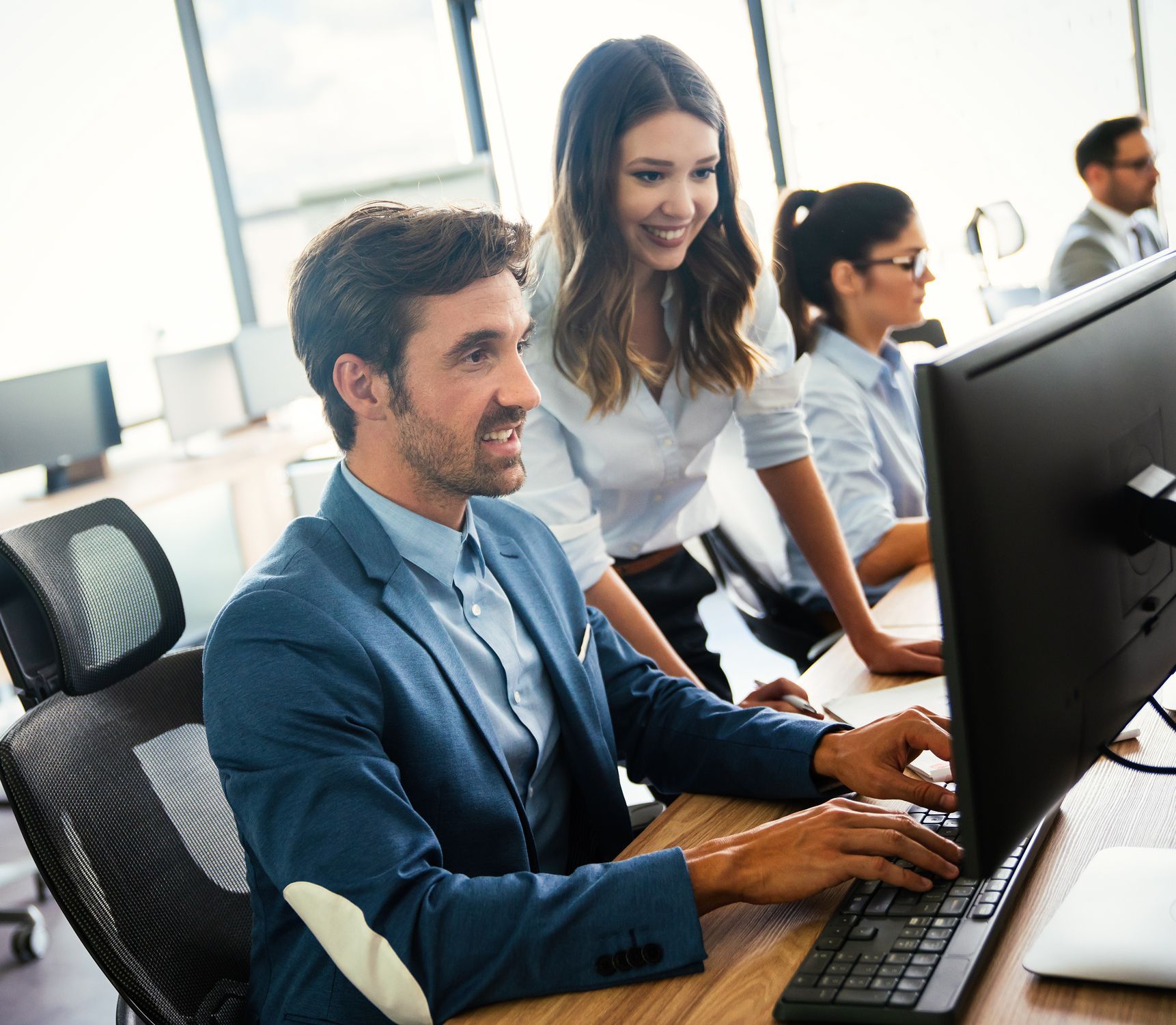 A man and a woman are looking at a computer screen.