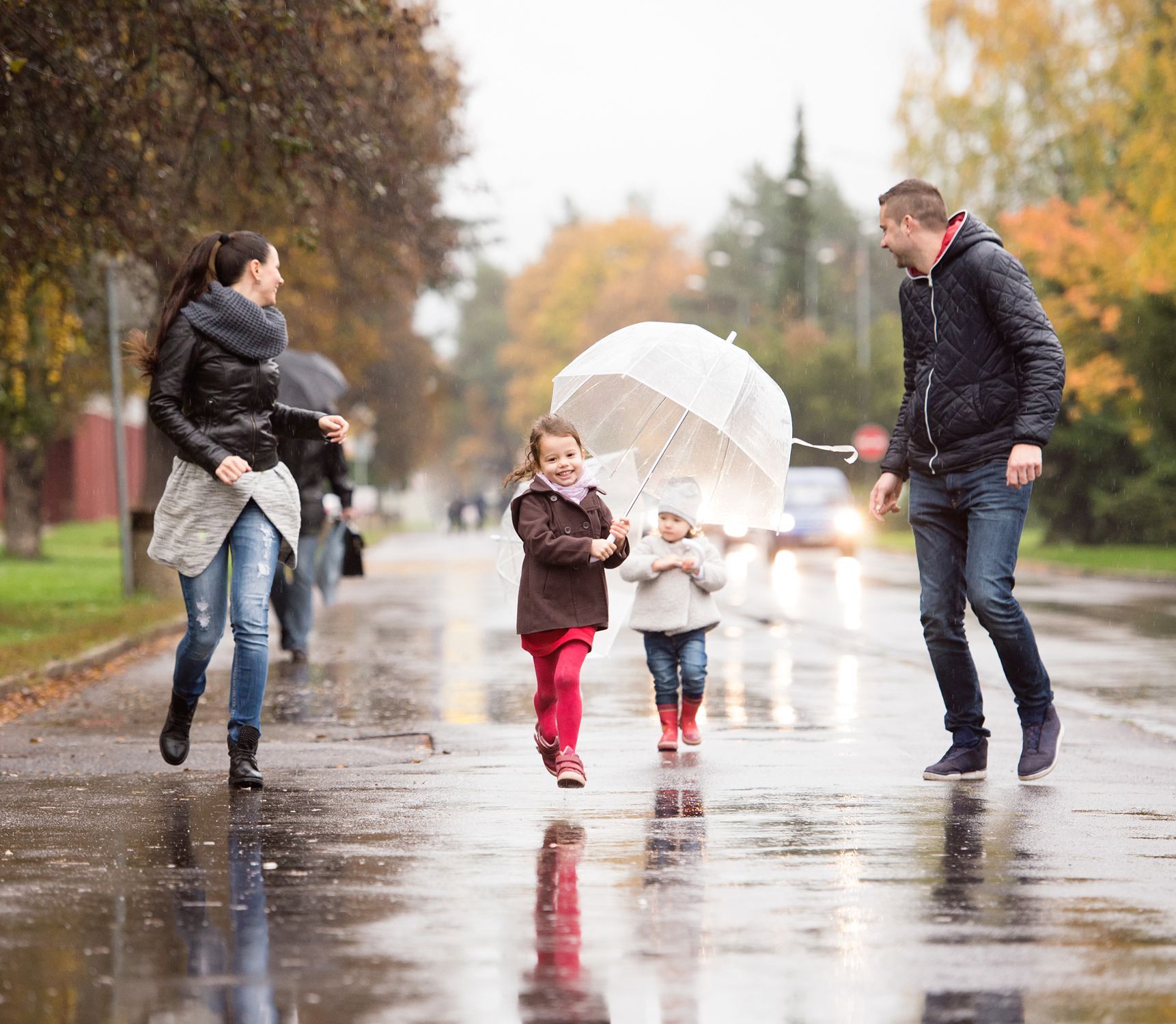 A family is walking down the street in the rain with umbrellas.