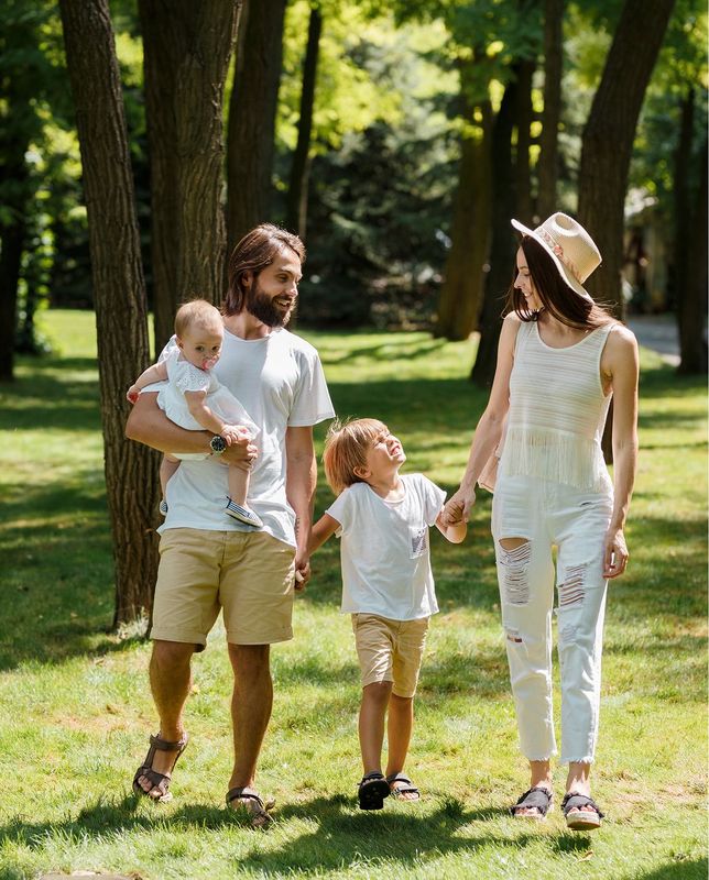 A family is walking through a park holding hands.