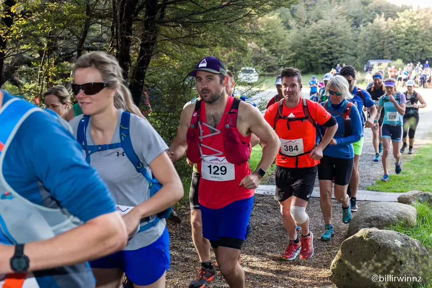 A group of people are running a race in the woods.